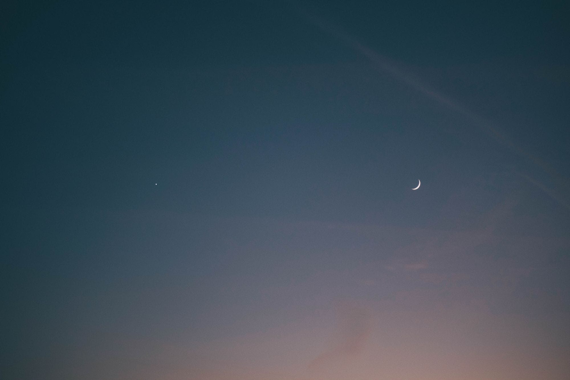 A tranquil scene of a crescent moon and star in the evening sky, evoking calmness and wonder.