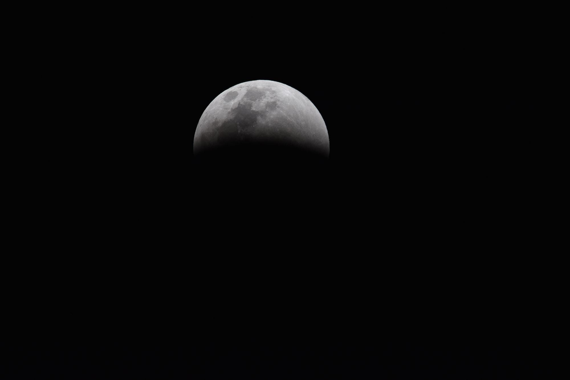 Dramatic view of a partial lunar eclipse showcasing the moon's shadowed surface against a dark sky.