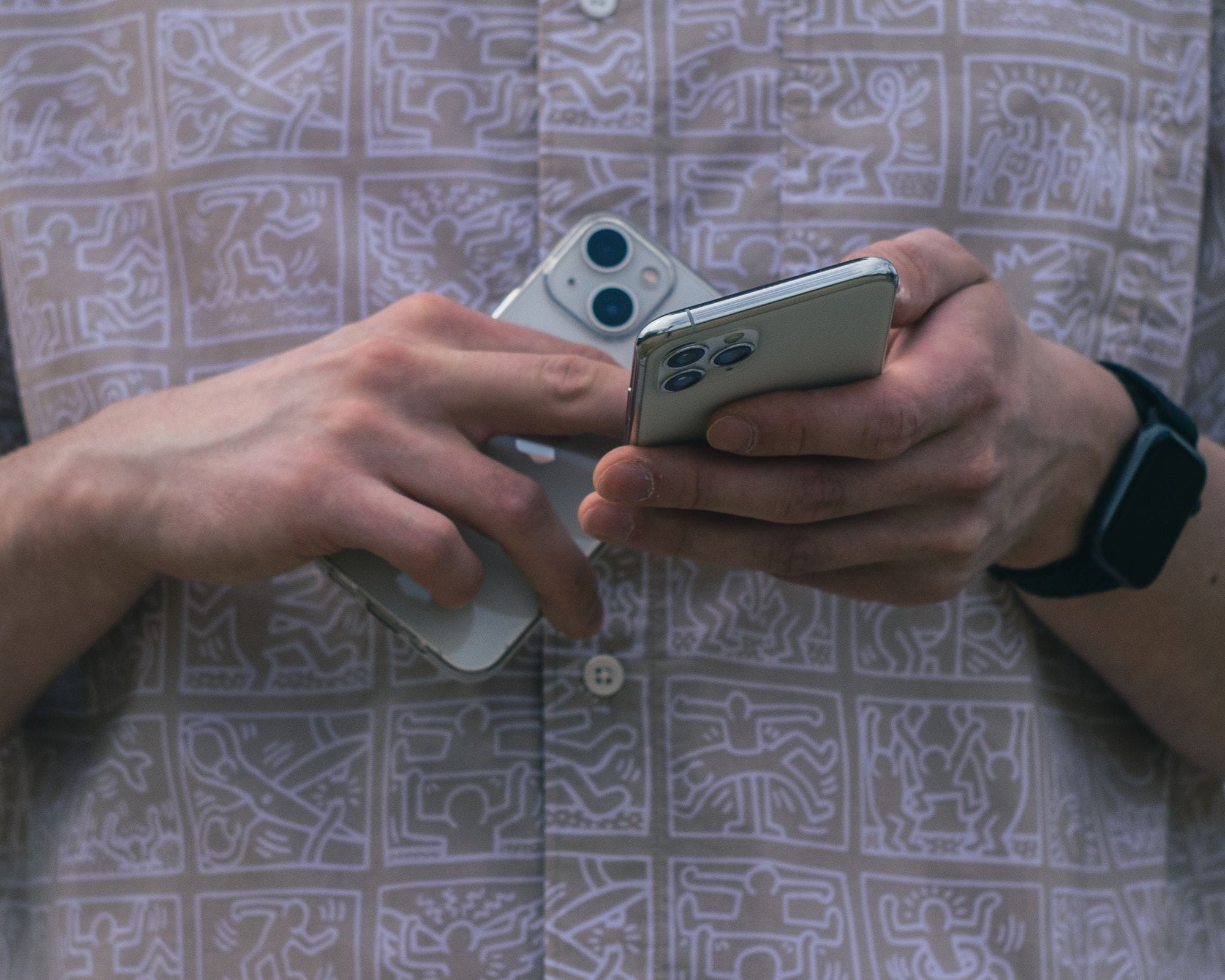 Detail of hands holding two smartphones, showcasing modern technology usage.