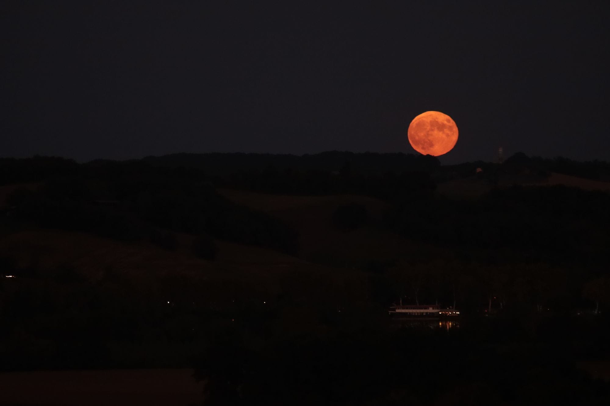 Captivating view of the full moon illuminating a serene landscape under a dark night sky.