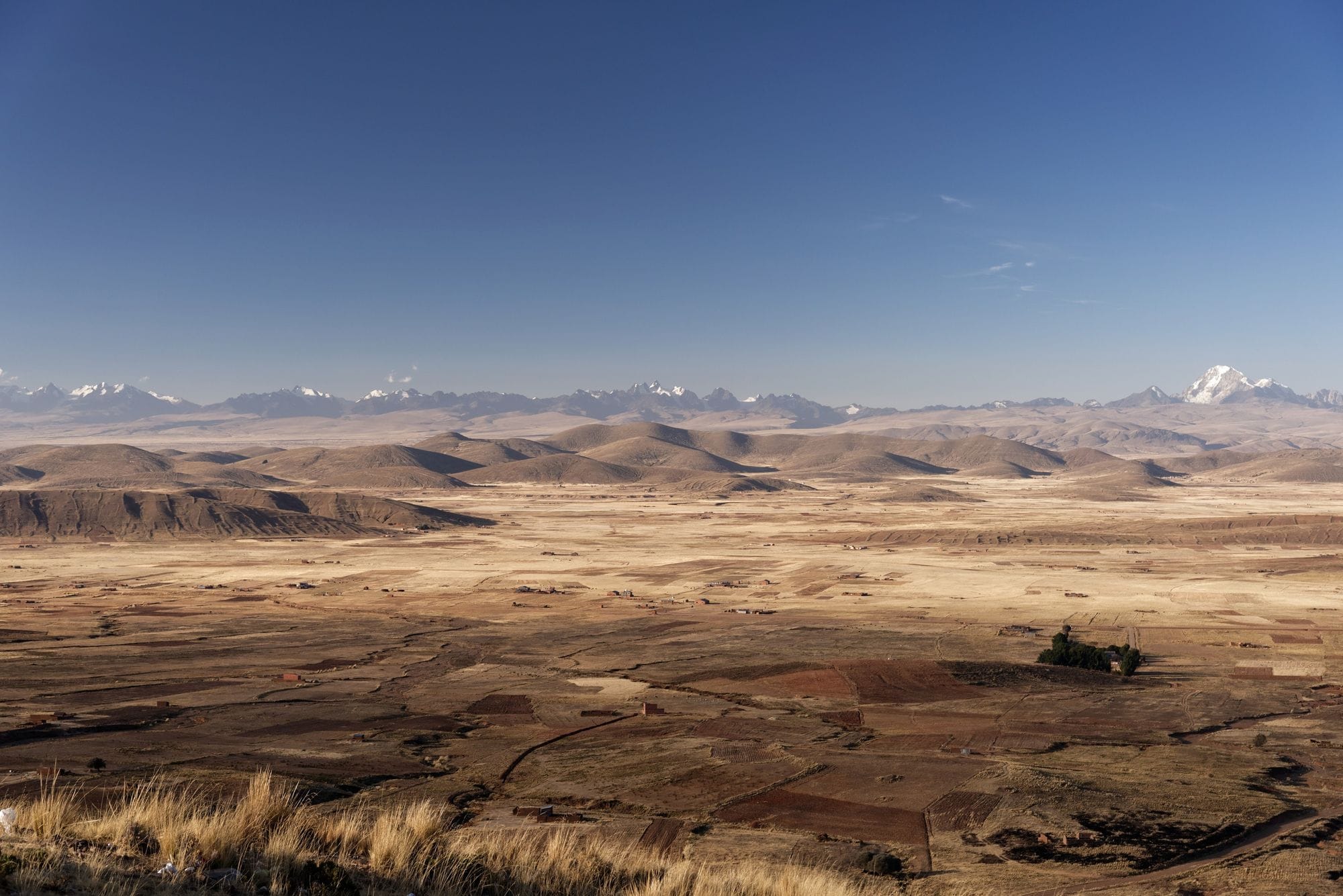 Panoramic view of the arid Andean plains with distant mountain ranges under a clear blue sky.