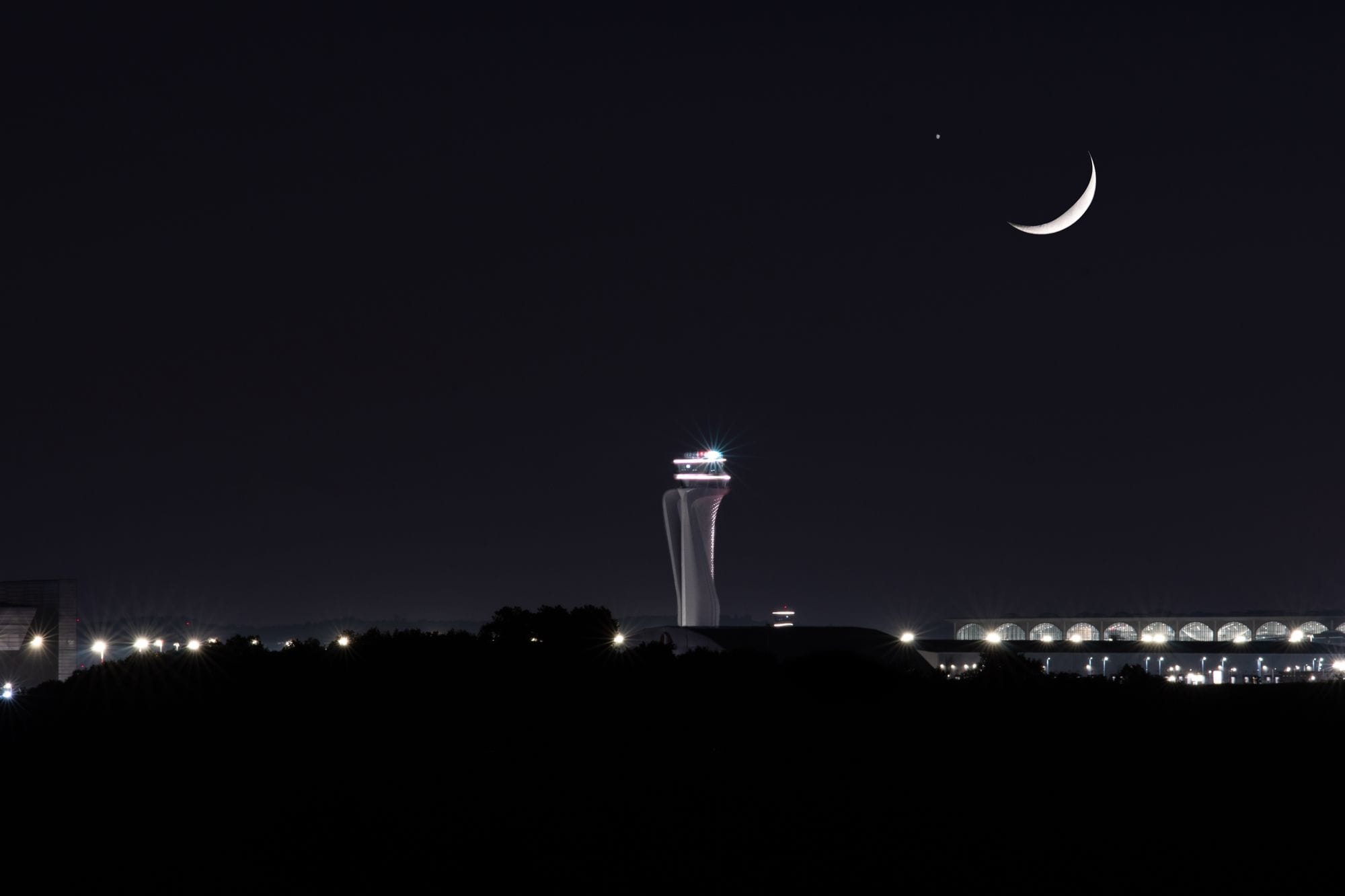 Crescent moon illuminating Istanbul Airport's control tower at night.