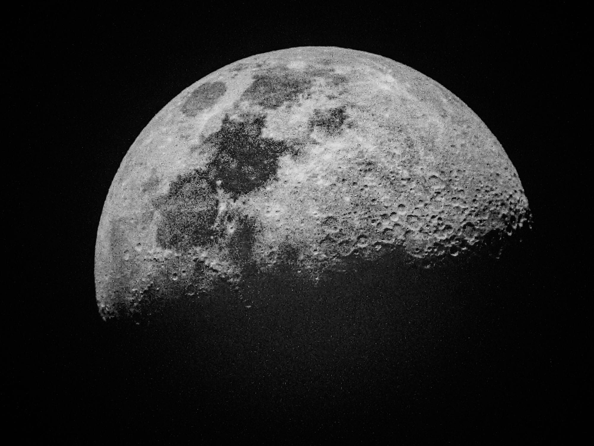 Detailed black and white photo of the moon's surface showing craters and texture.