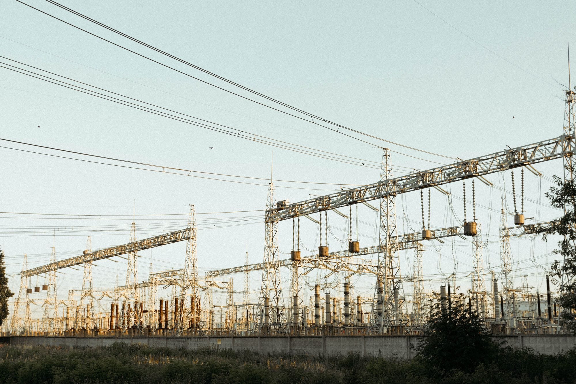 A wide view of an industrial electrical substation with power lines and towers outdoors.