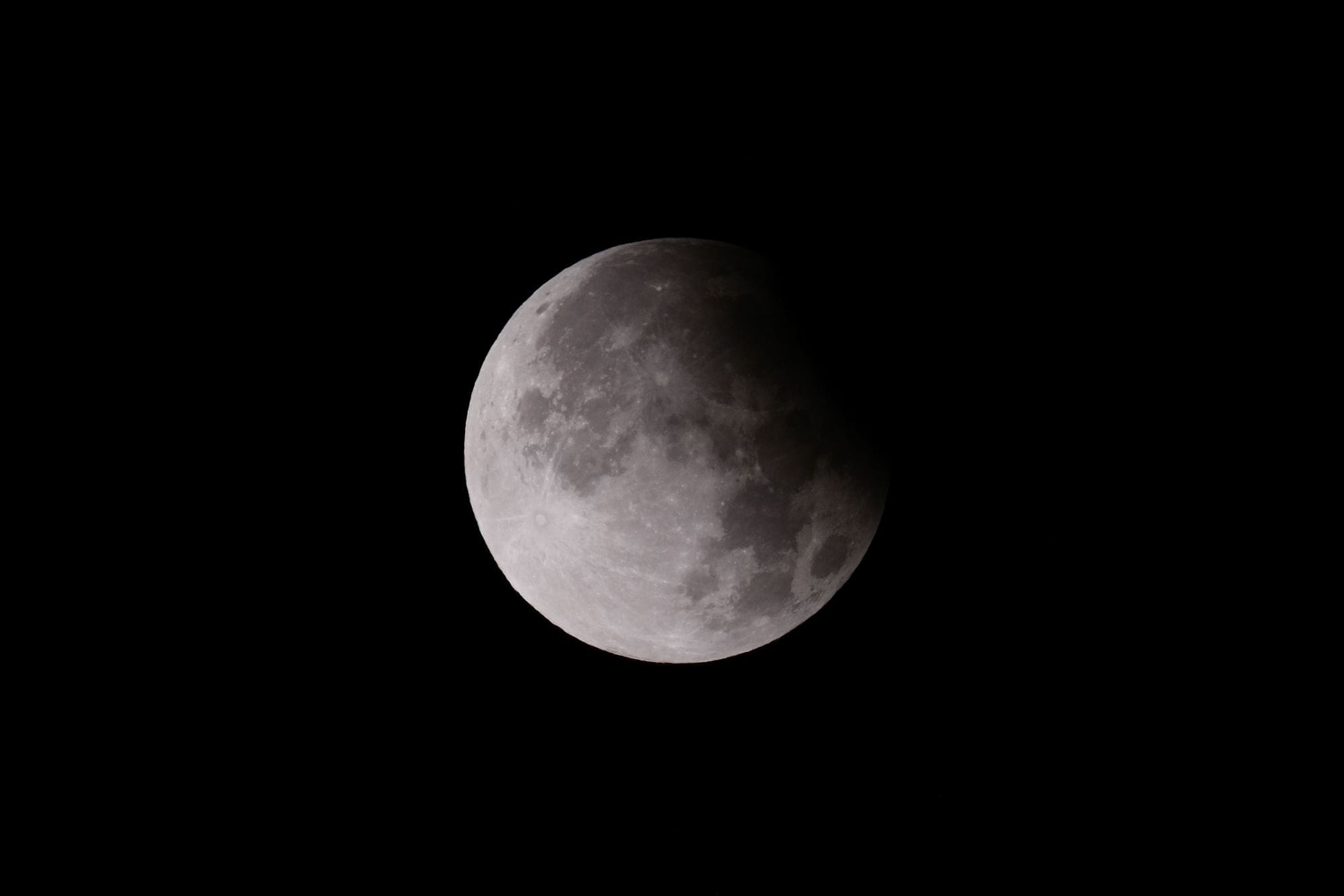 Close-up shot of a lunar eclipse, showcasing the moon's surface with shadow play.