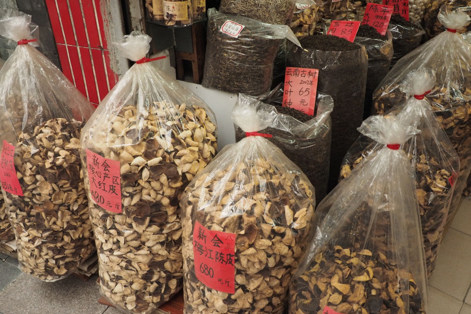 Bags filled with dried mushrooms and tea at an outdoor market stall.