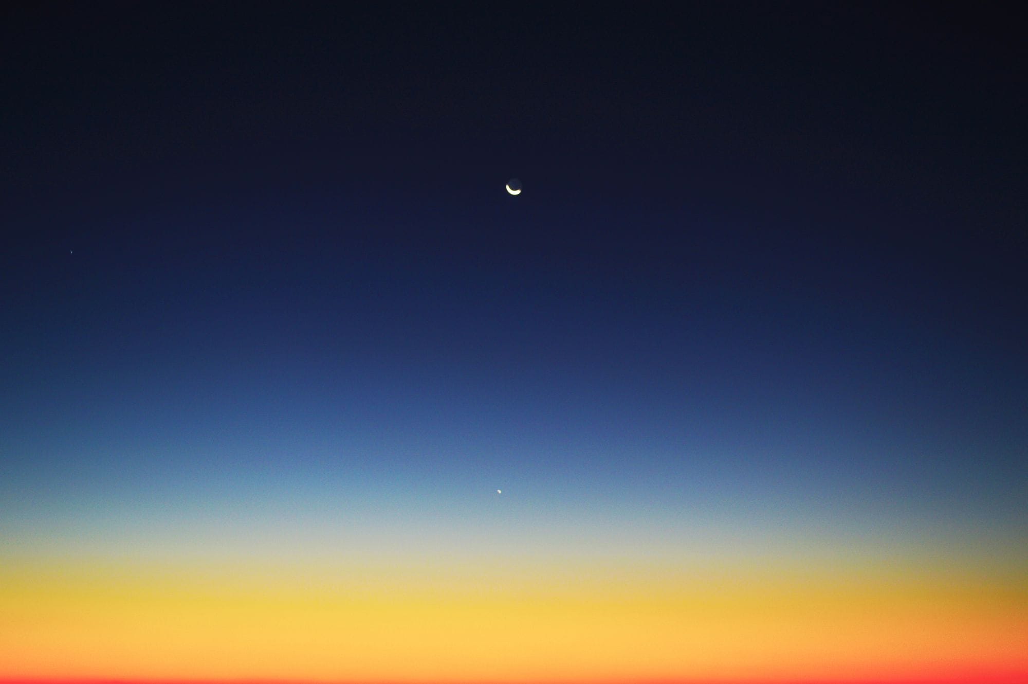 Crescent moon and planet visible in a colorful twilight sky over Mahajanga, Madagascar.