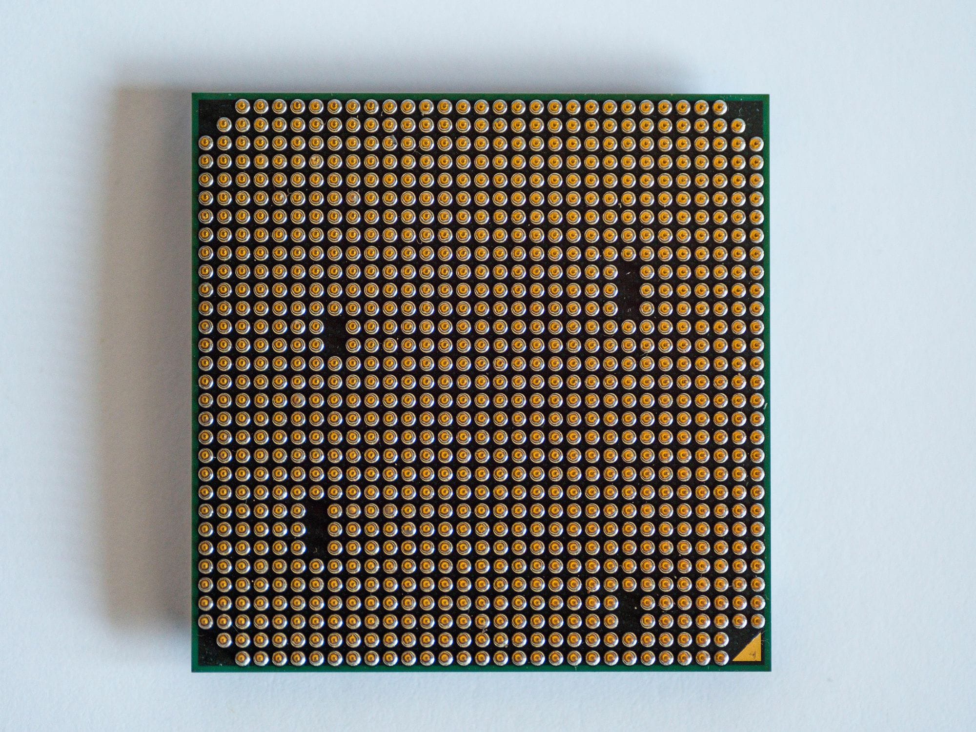 Detailed view of a computer processor, showcasing its pins, against a clean white backdrop.