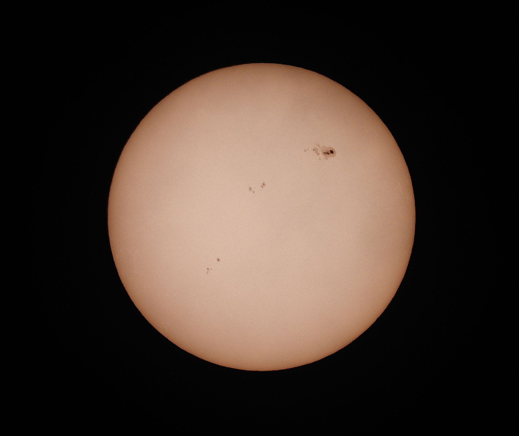 A detailed photograph of the sun highlighting visible sunspots against a dark background.