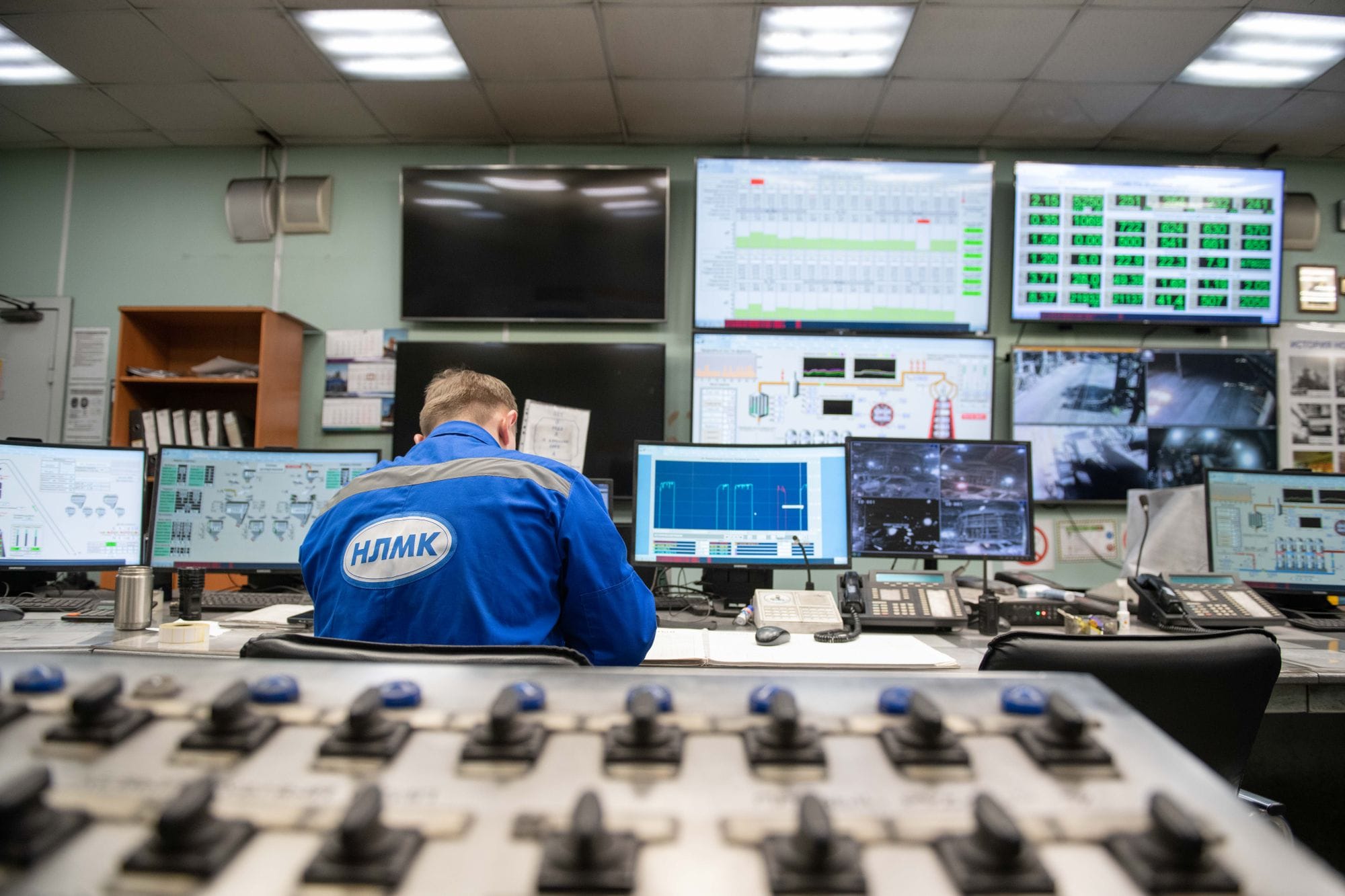 An engineer monitors multiple screens in an industrial control room, ensuring smooth operations.