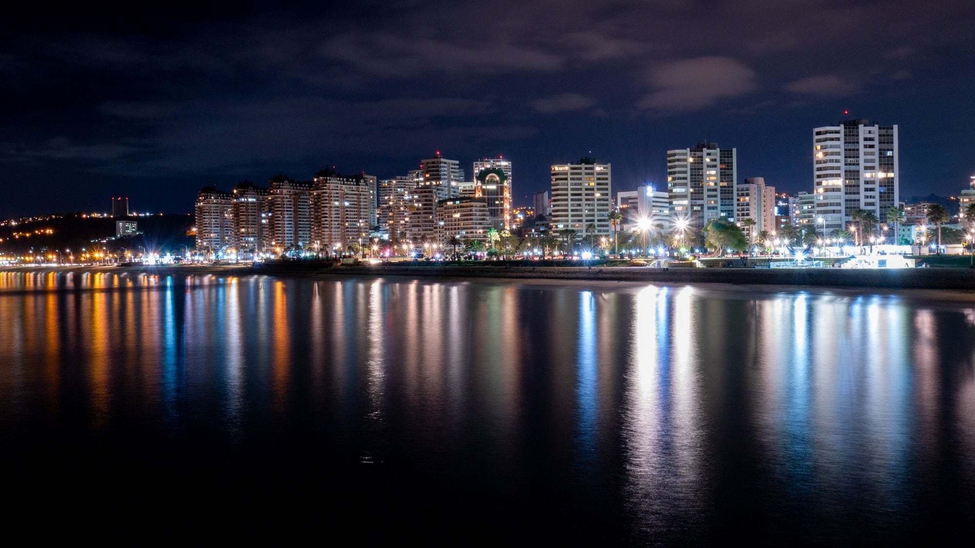 Captivating night cityscape of Viña del Mar with lights reflected over the ocean.
