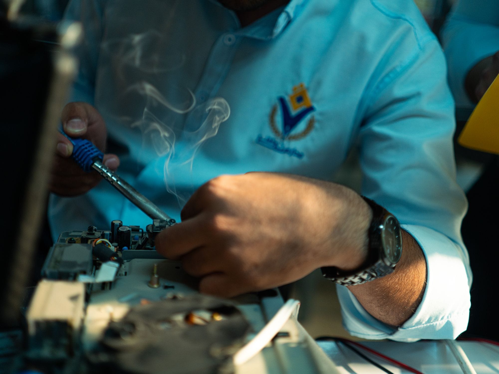Technician focused on soldering electronics, showcasing precision and skill in technology repair.