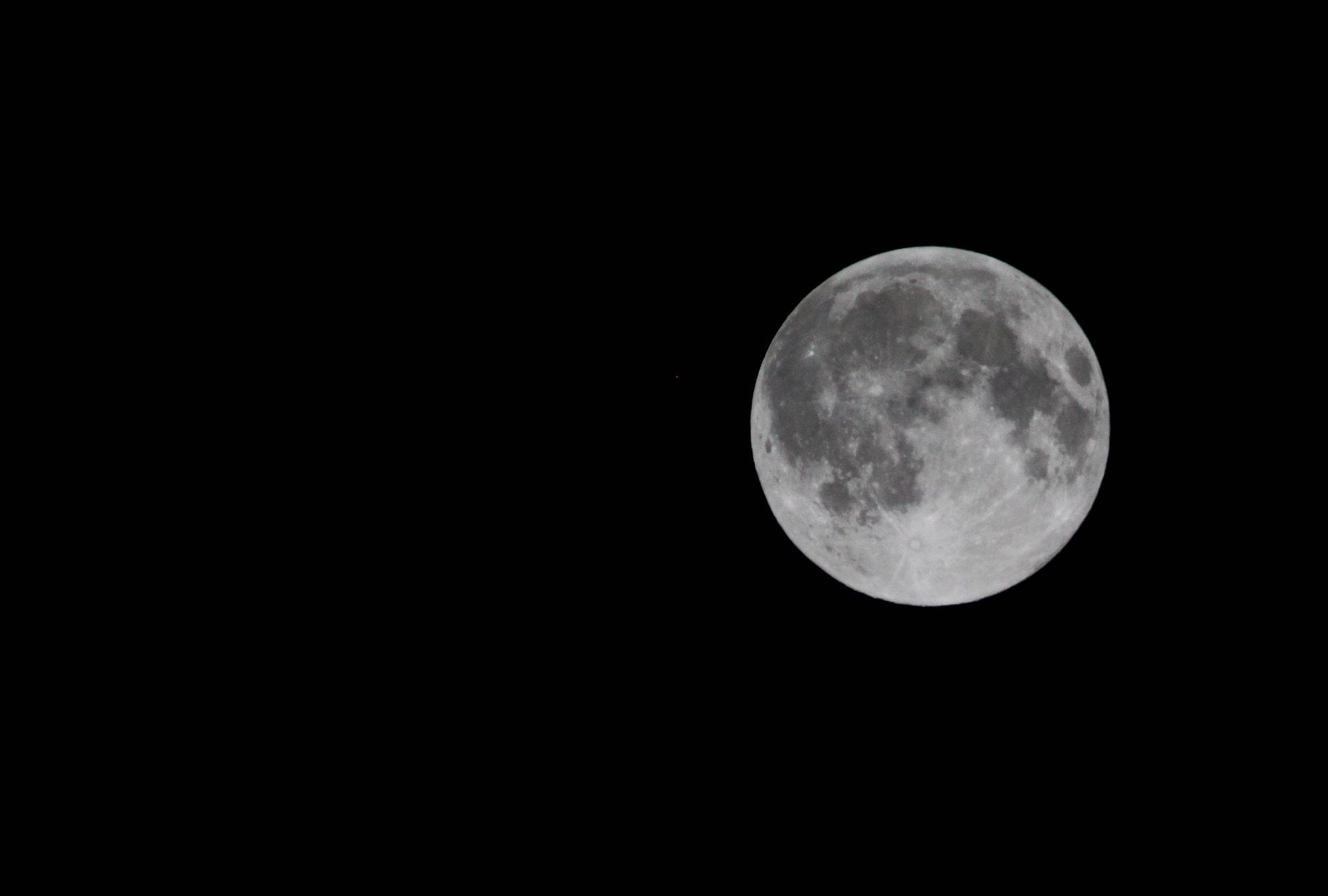 A full moon shines bright against a dark night sky, showcasing its details and craters.