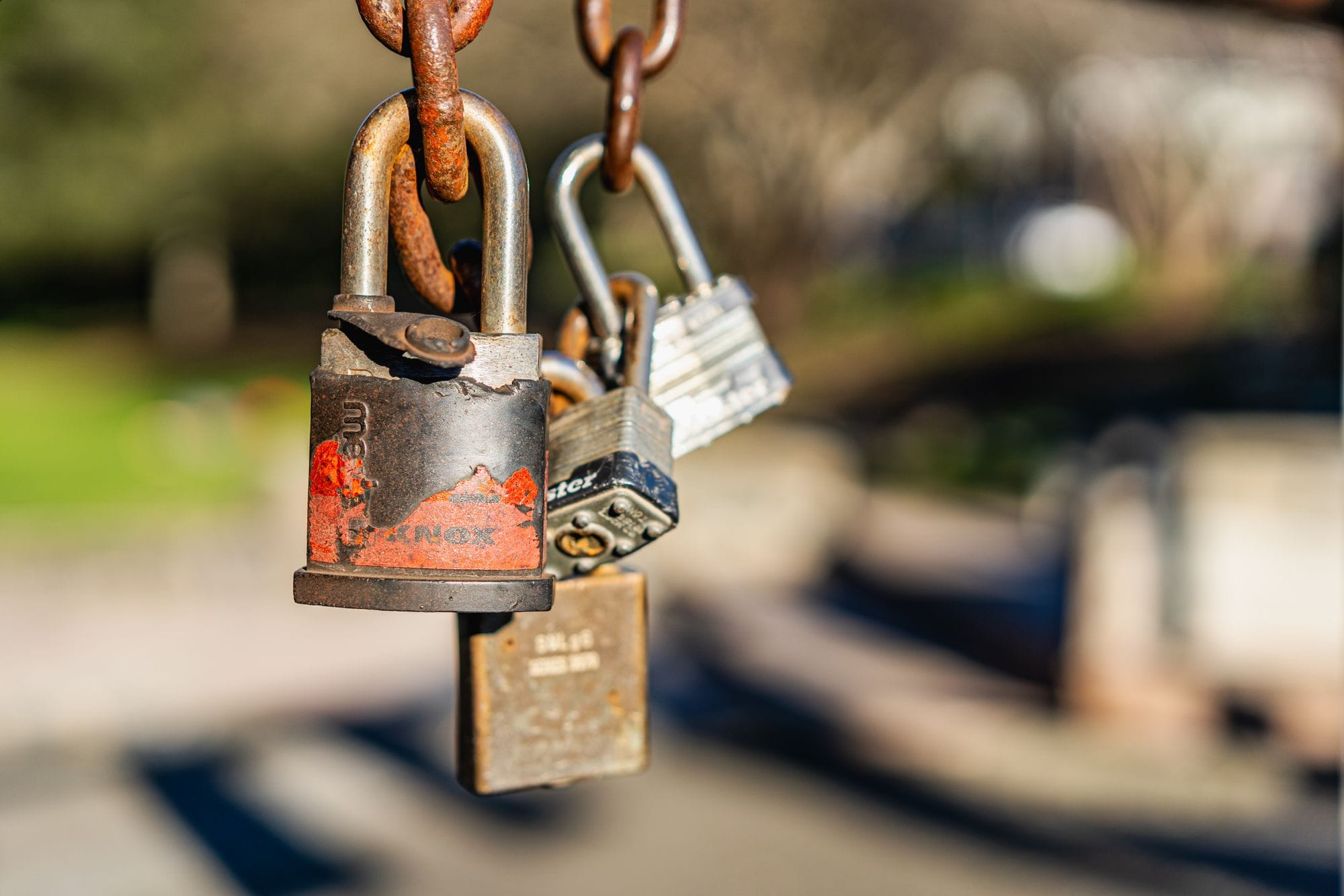 Macro shot of rusty padlocks hanging on a chain, symbolizing security and neglect.