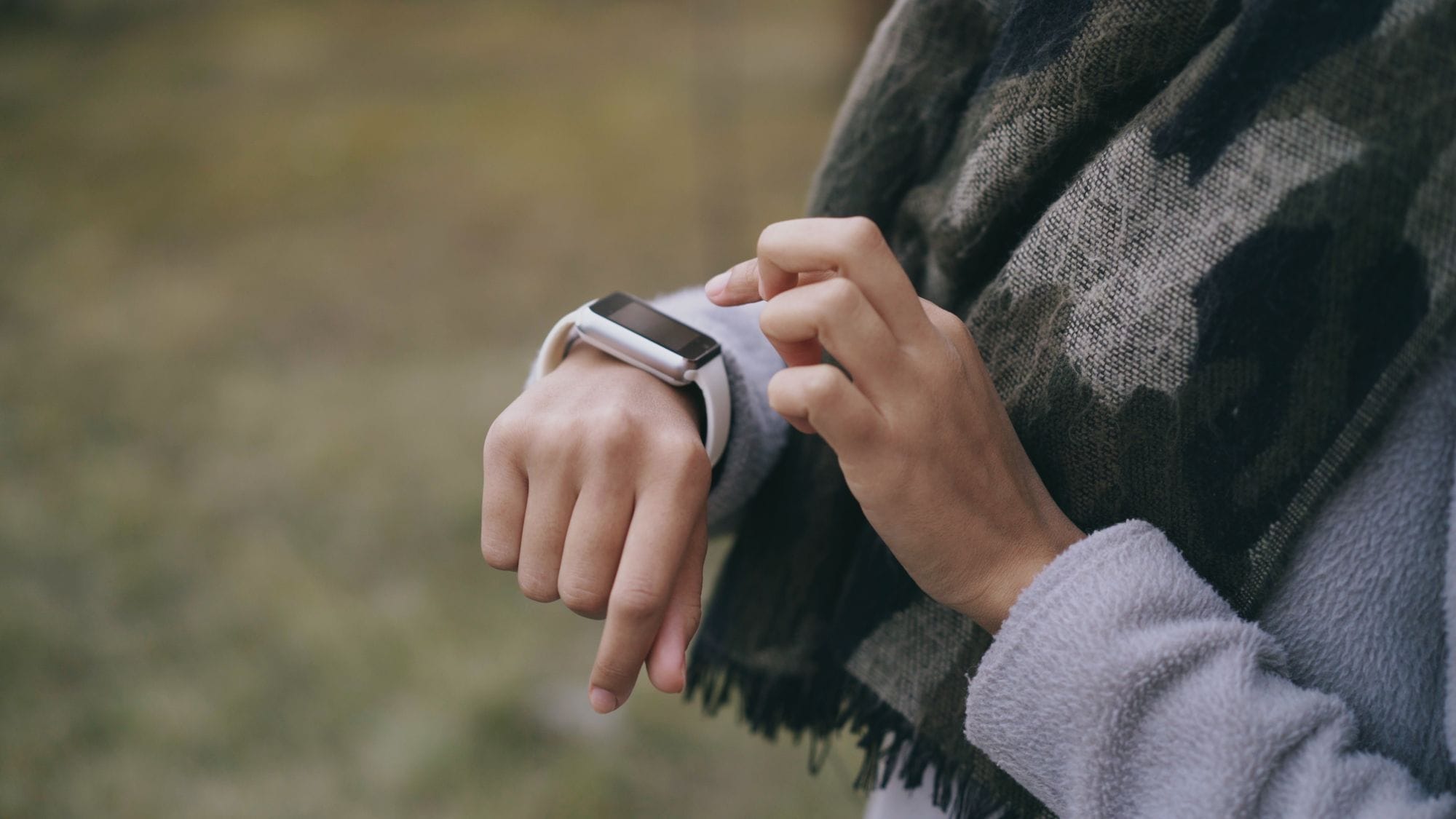 Close-up of a person using a smartwatch outside.