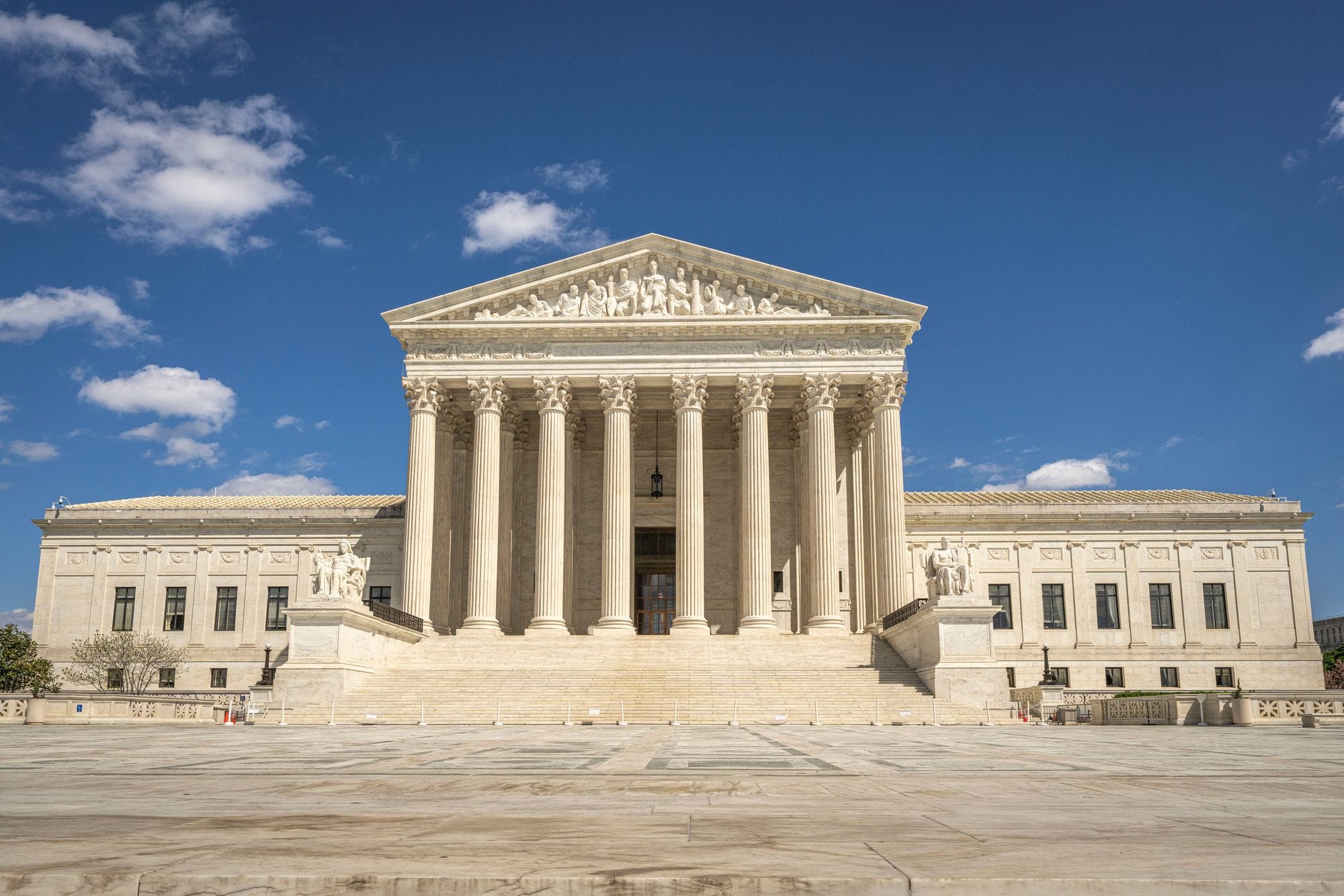The majestic facade of the United States Supreme Court under a clear blue sky.