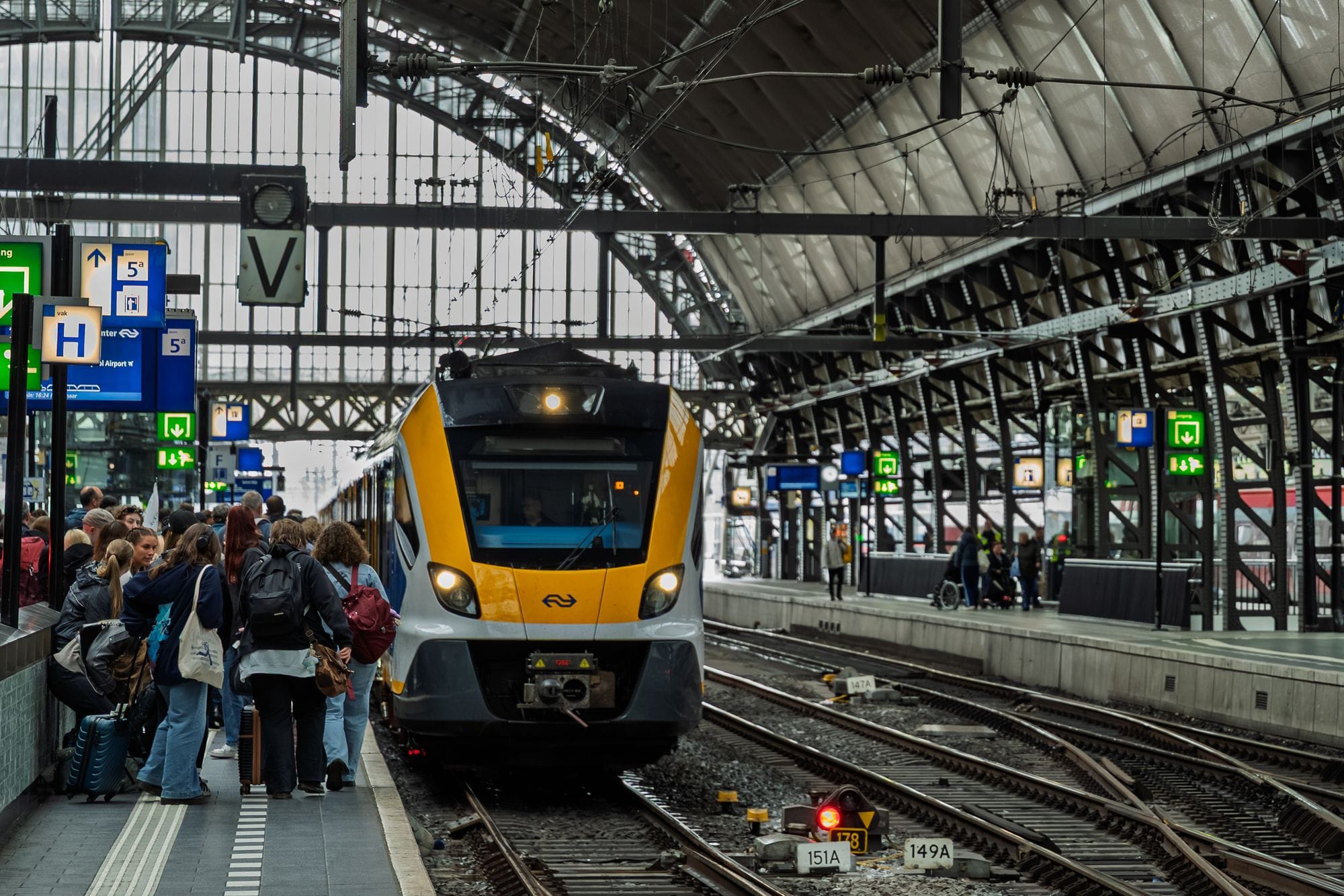 Crowded platform at Amsterdam Central Station with train arriving, capturing daily urban commute scene.