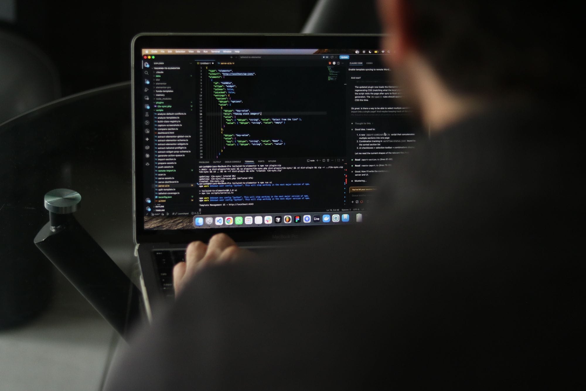 A focused developer writing code on a laptop in an indoor workspace.