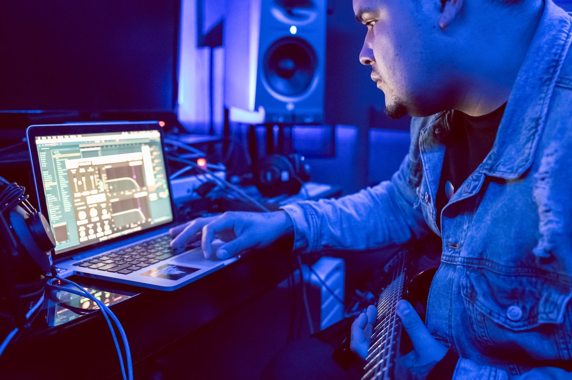 Young musician using laptop for music production in recording studio.