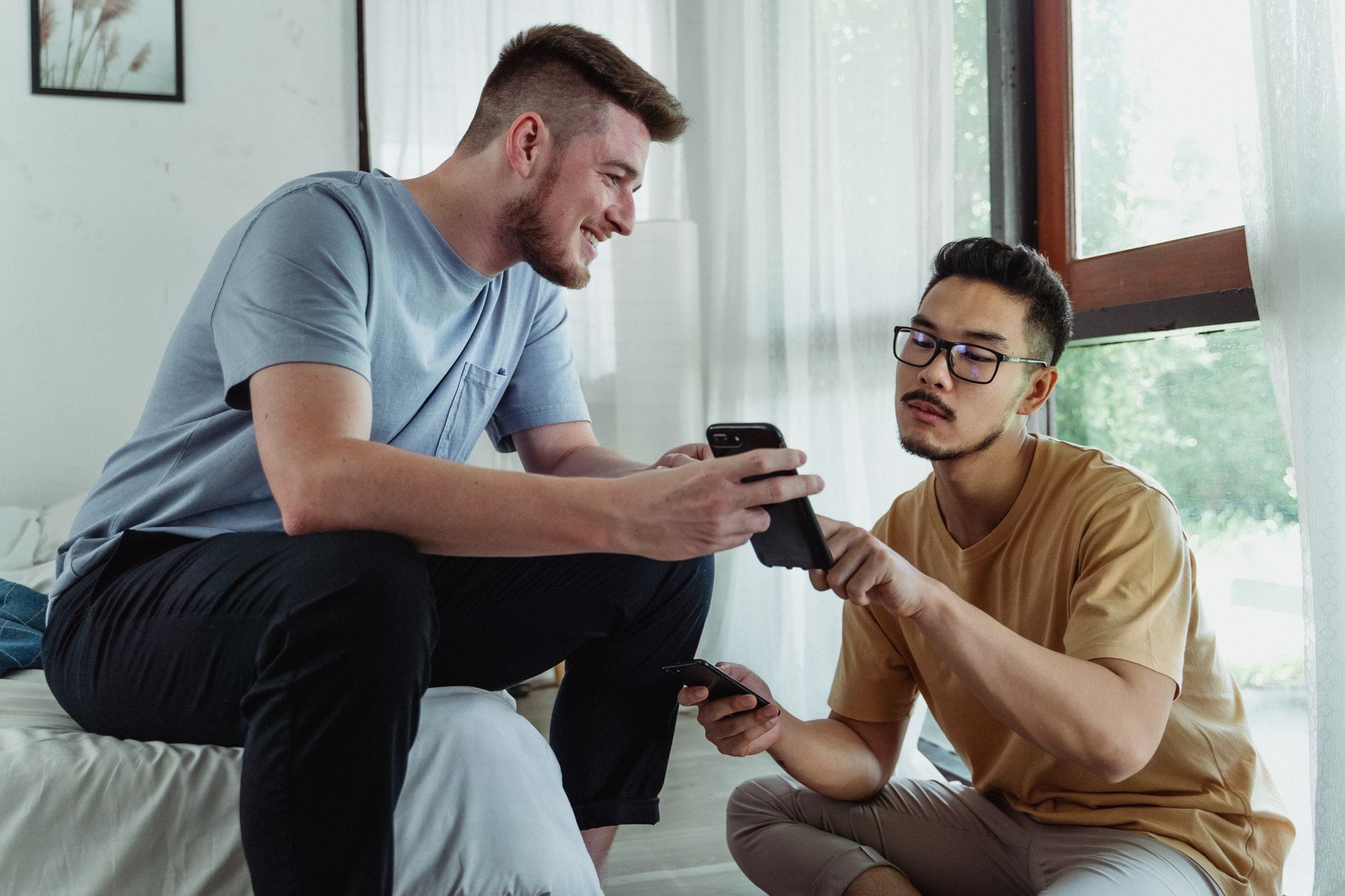 Two young men using smartphones, collaborating in a cozy room setting.