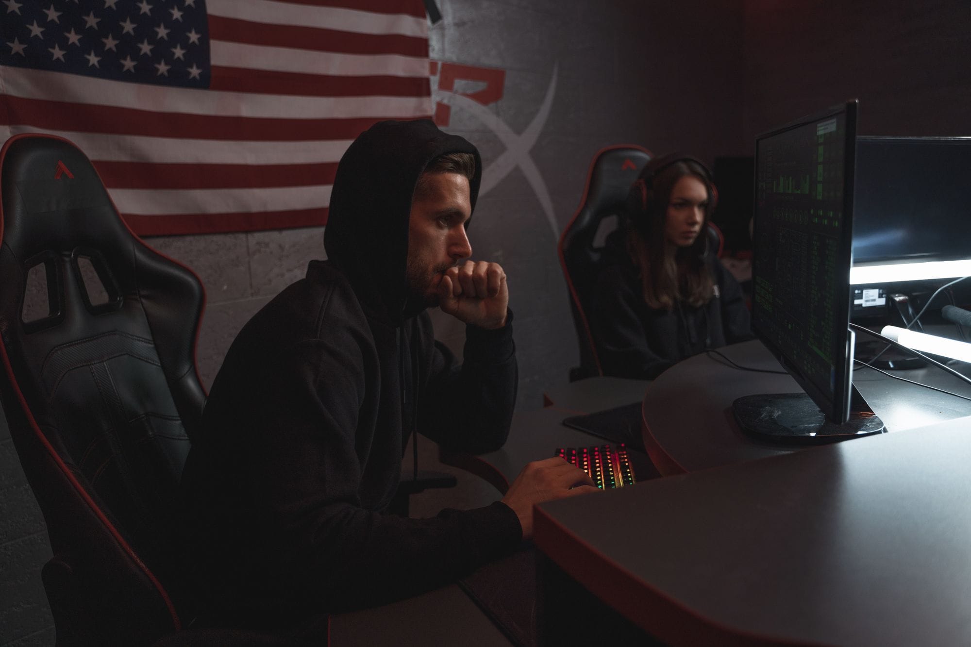 Two individuals analyze data in a dimly lit cybersecurity setting, highlighting digital defense themes.