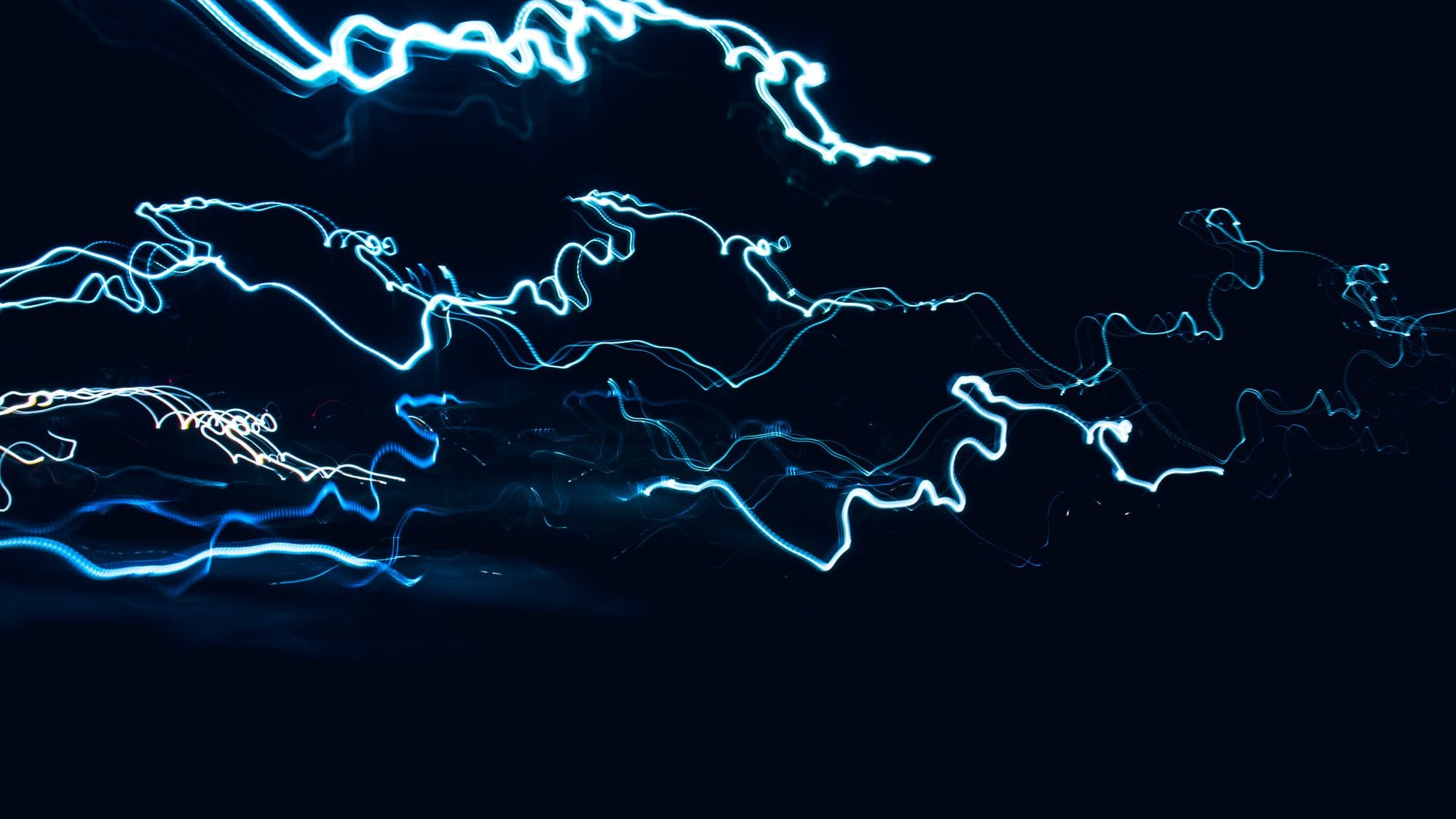 Dynamic abstract design of blue light streaks over black backdrop, capturing movement.