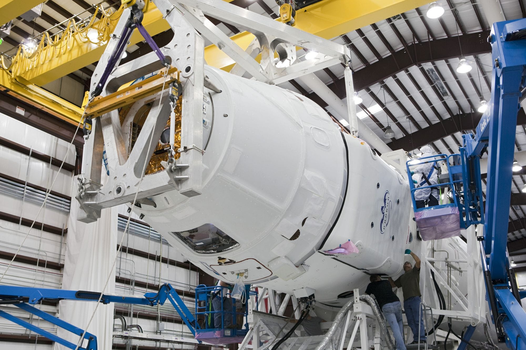 Low angle of unrecognizable technicians inspecting detail of new rocket booster at industrial space factory