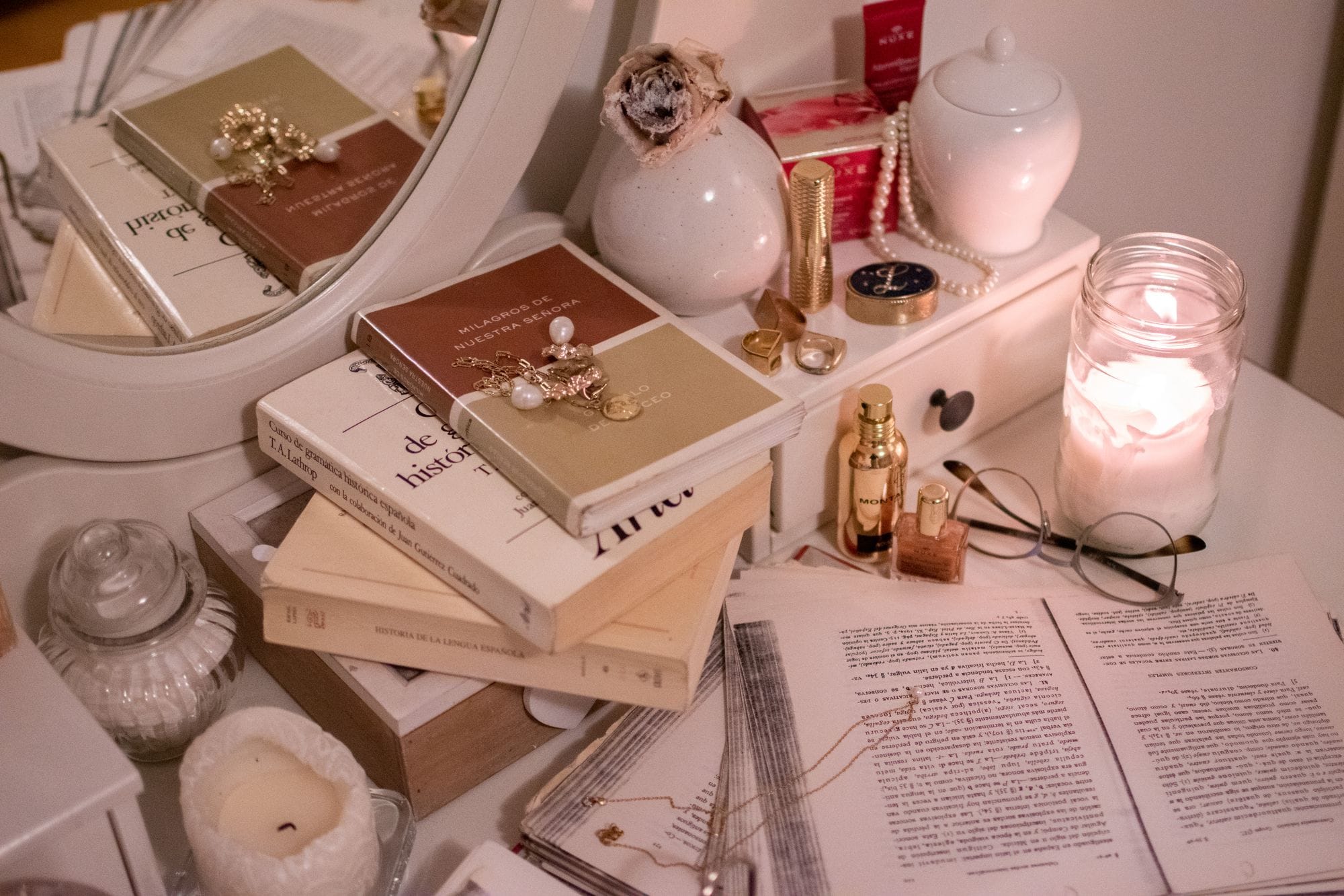 A warm, serene arrangement with books, candle, and decorative objects on a table.