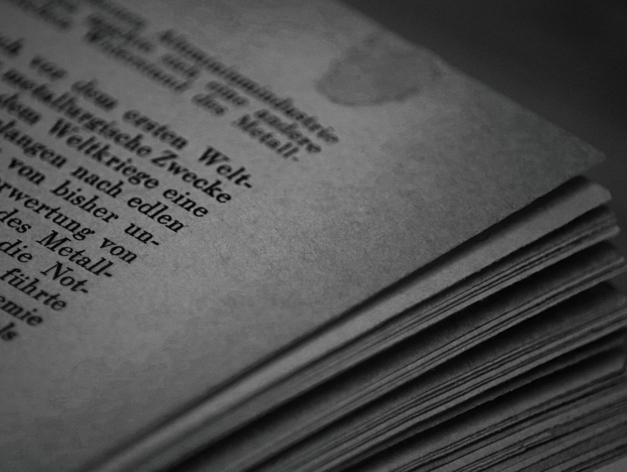 Monochrome close-up of book pages with German text, showcasing texture and typography.