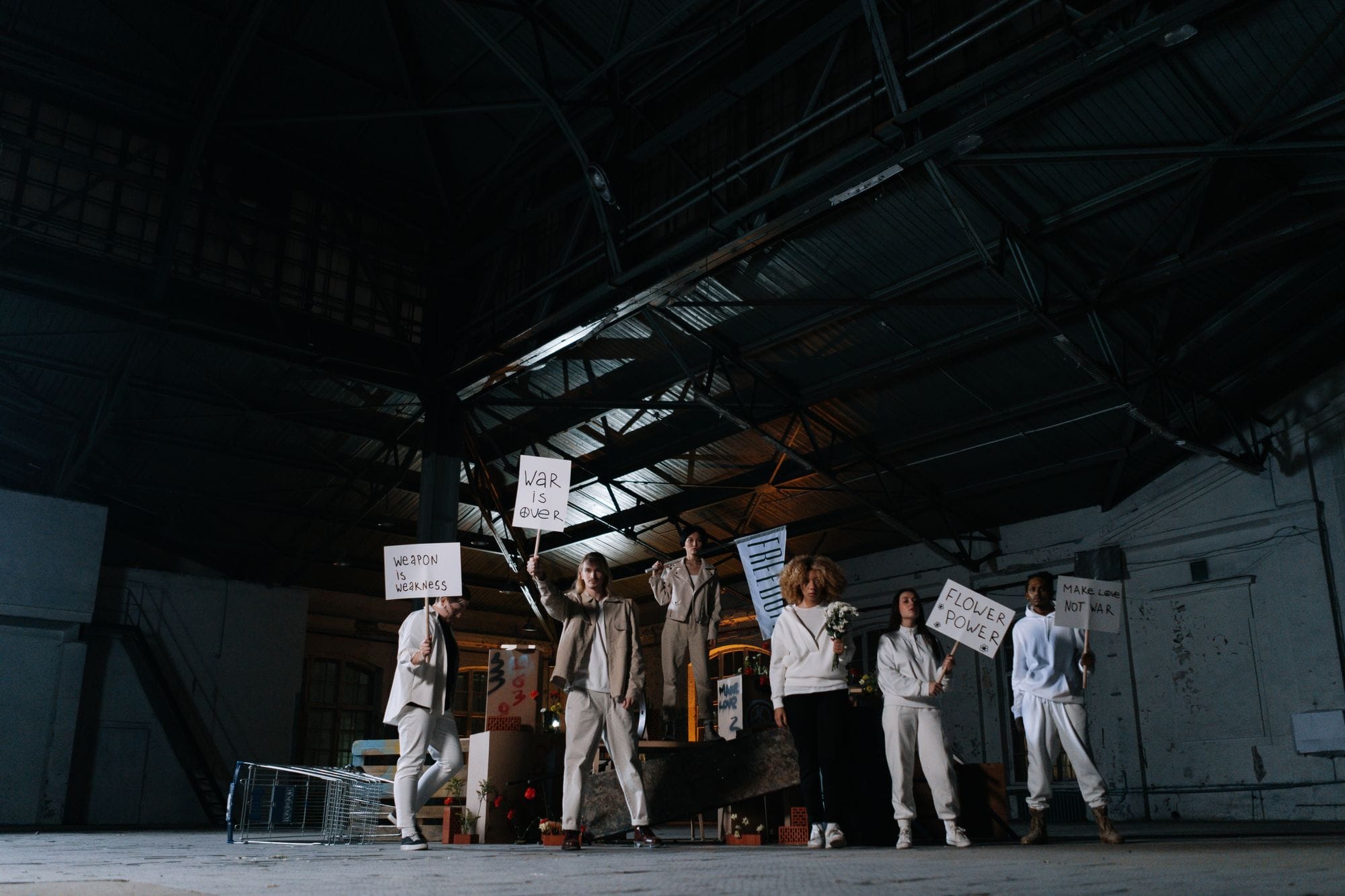A group of activists holding placards in a warehouse demanding peace.