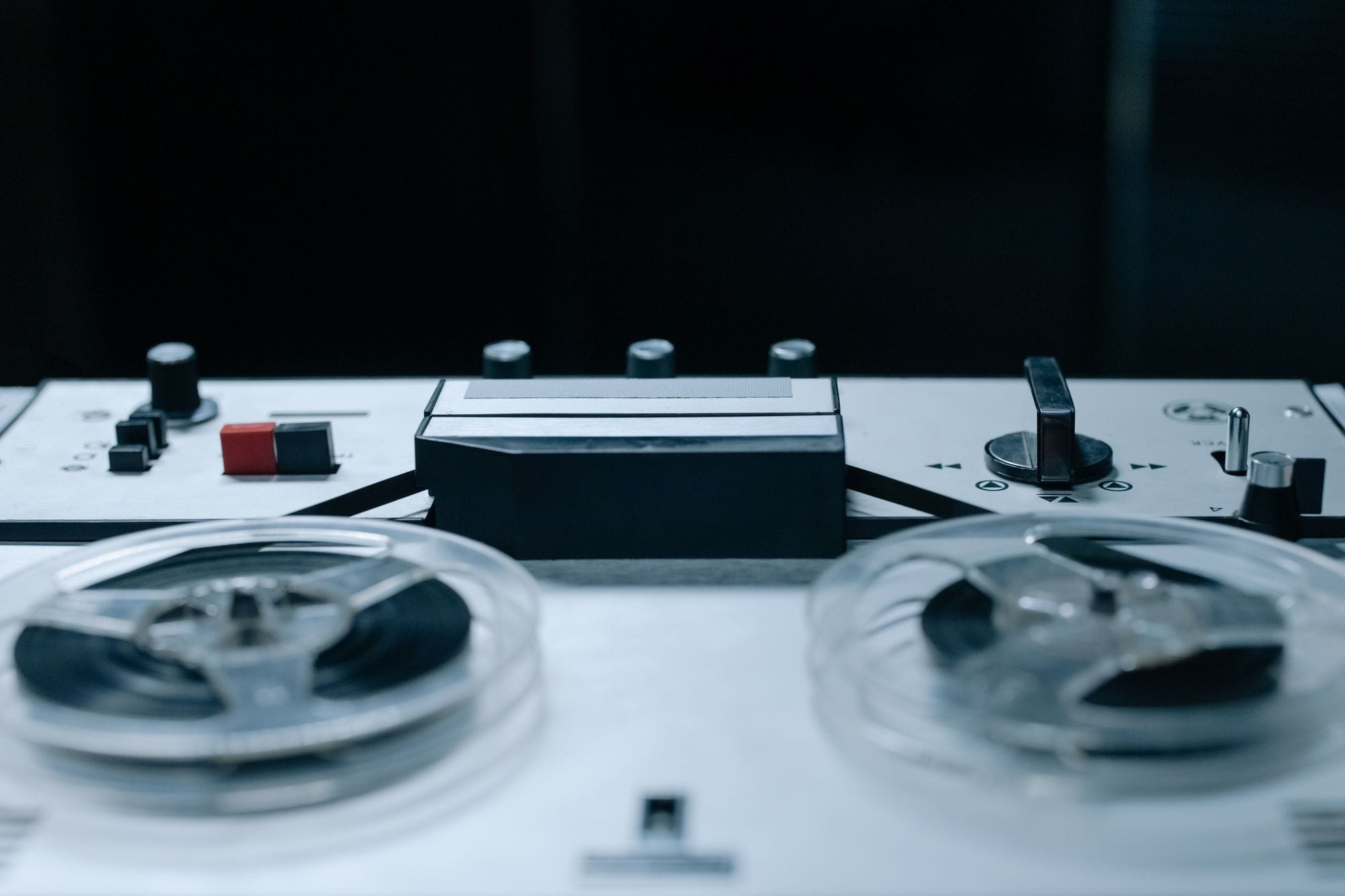 Close-up image of a vintage reel-to-reel audio recorder with control buttons and tape reels.