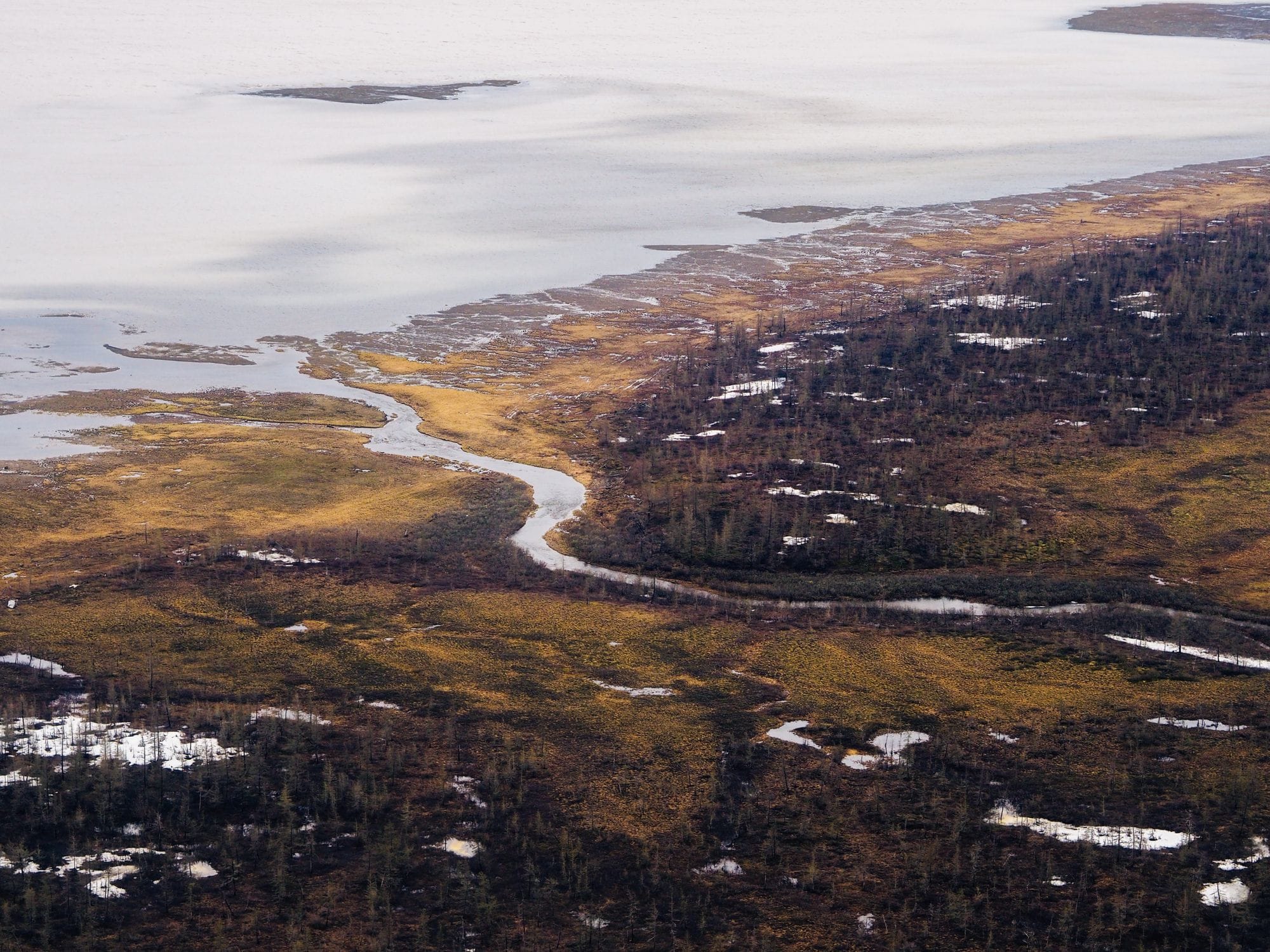 Stunning aerial view of Norilsk's natural landscape with thawing snow and winding waterways.