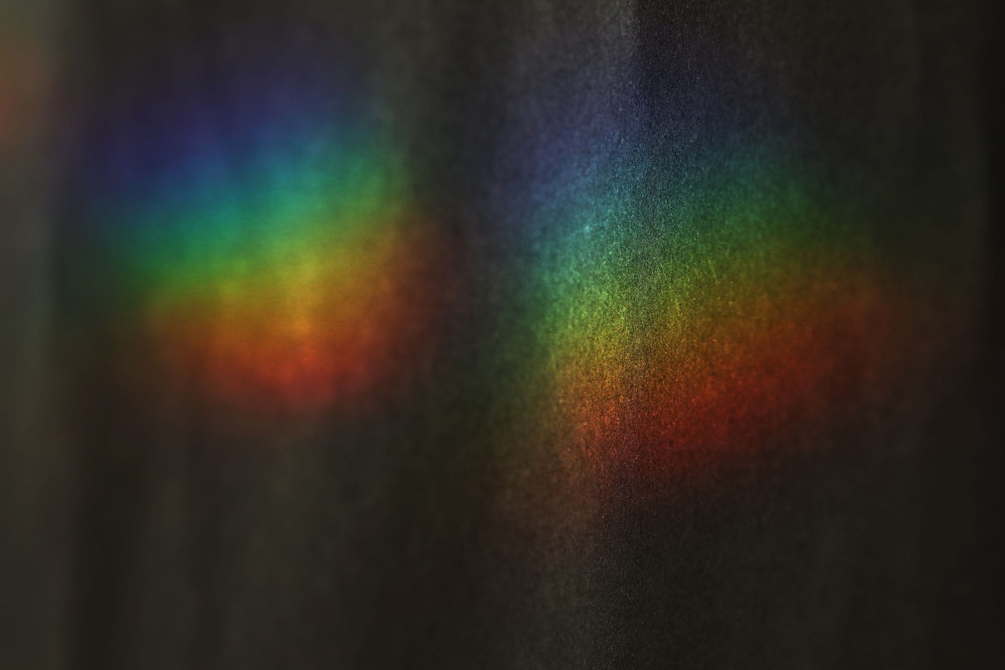 Vibrant rainbow colors from a light prism create an abstract display on a dark background.
