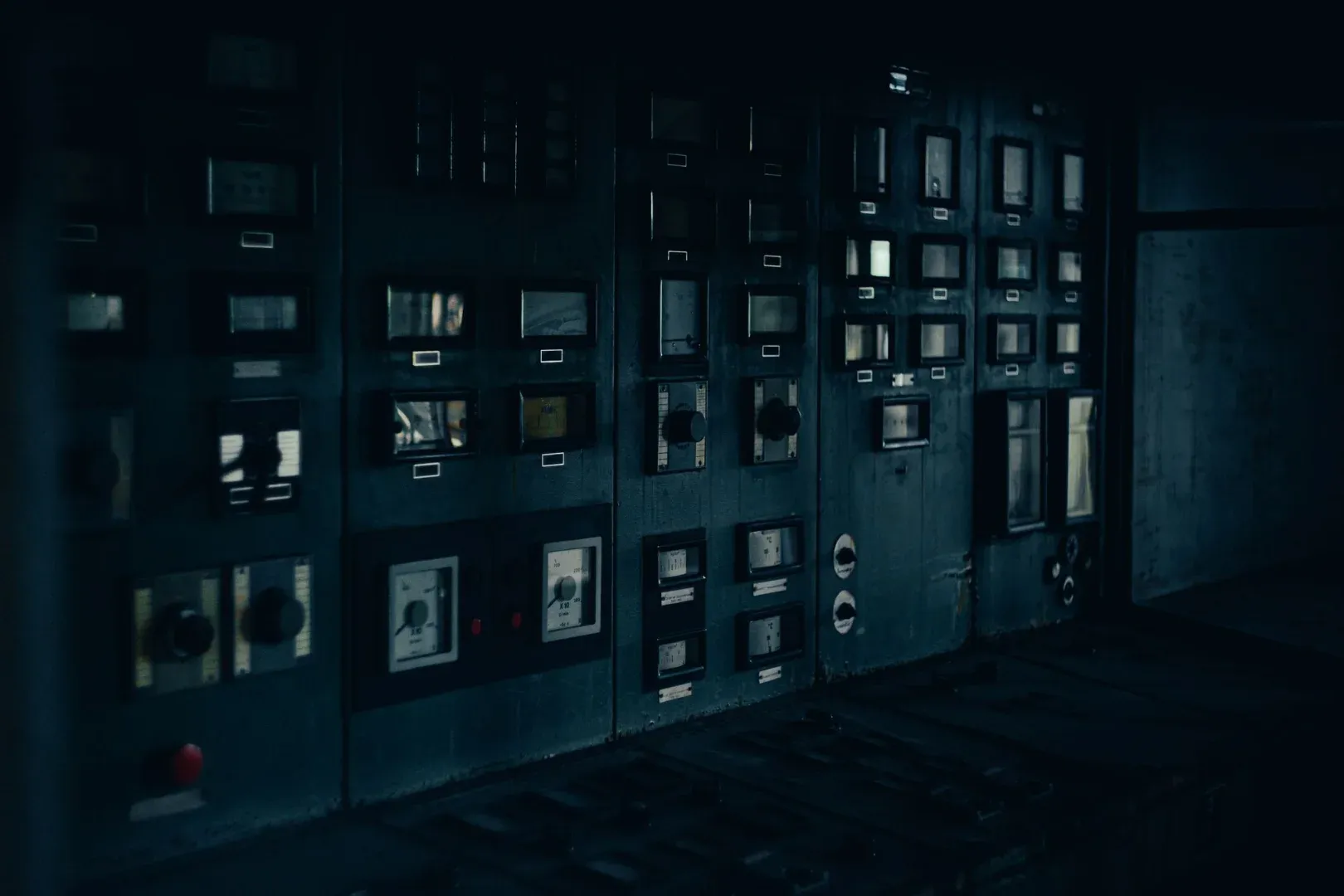 A dark, retro industrial control panel with dials and gauges in a maintenance room.