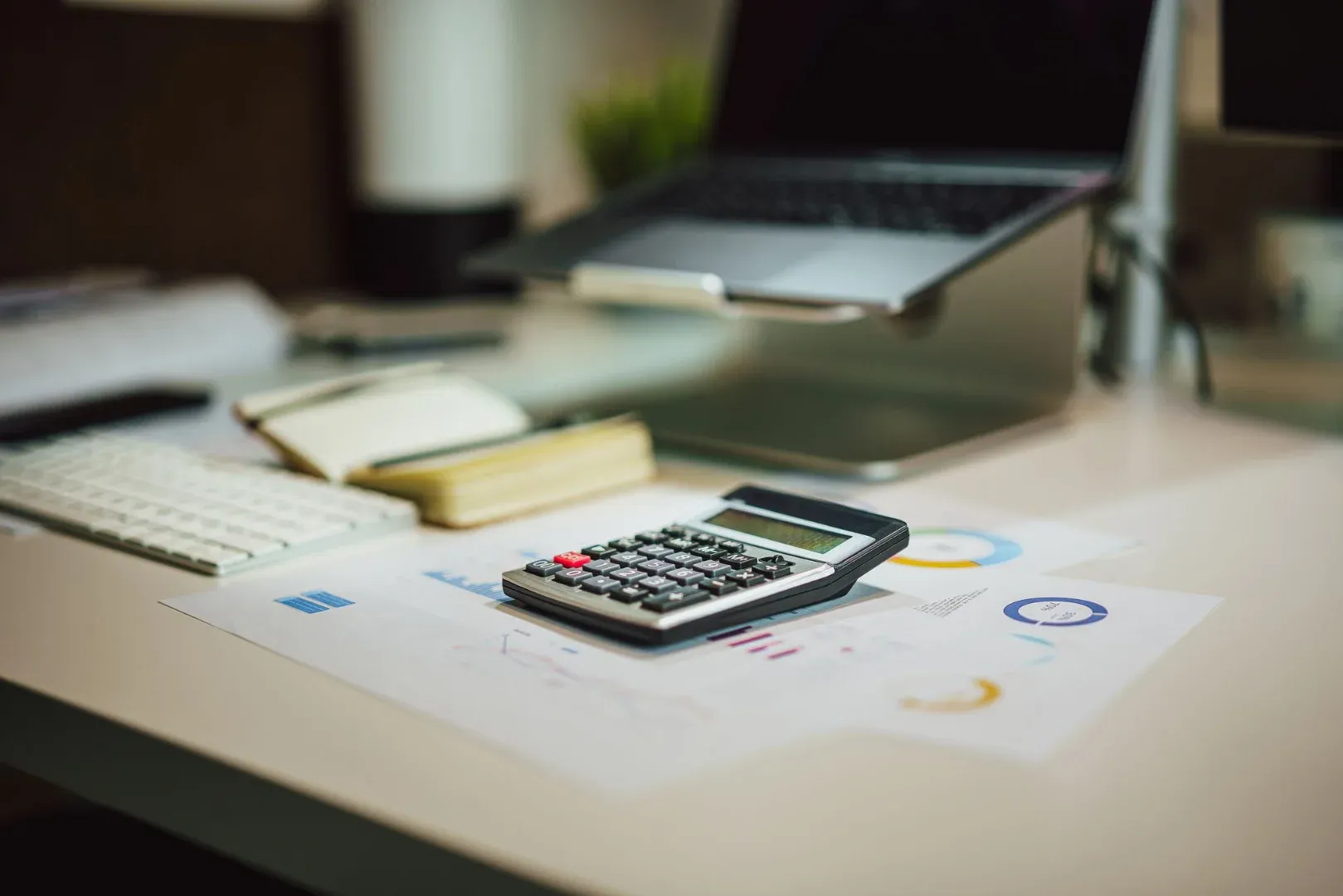 A modern workspace with a laptop, calculator, and documents on a desk, perfect for finance tasks.
