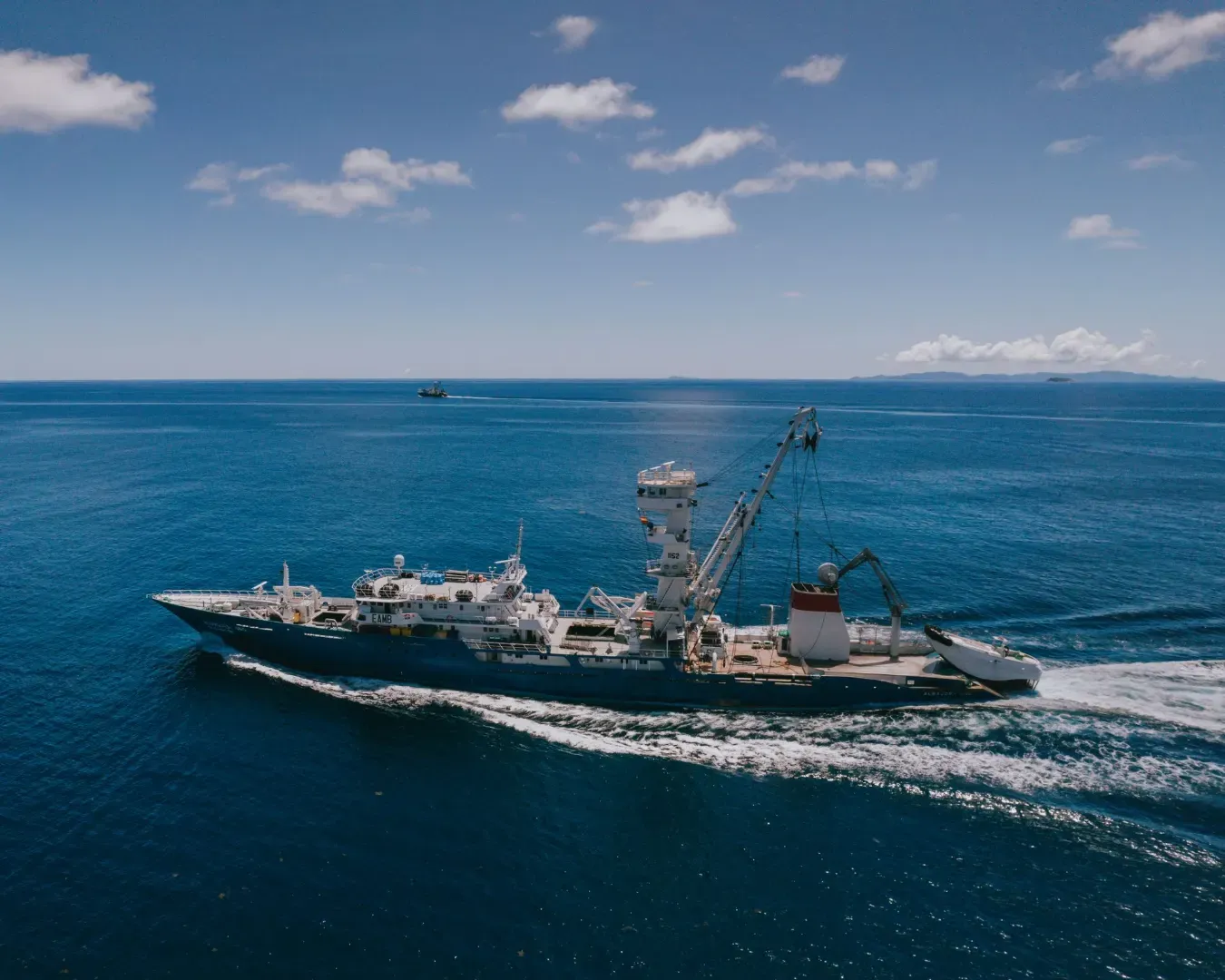 A ship cruising across the vast ocean under a bright blue sky near Seychelles.