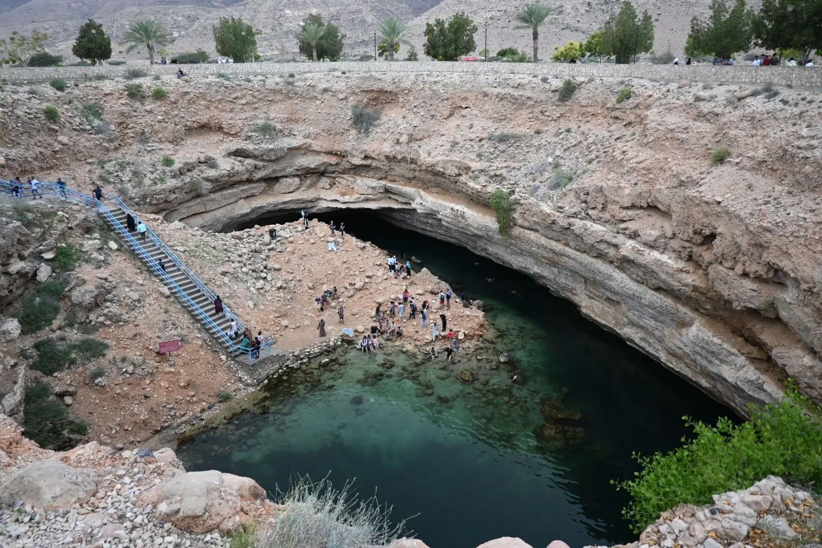 Aerial view of the Bimmah Sinkhole in Oman with tourists enjoying the stunning natural pool.