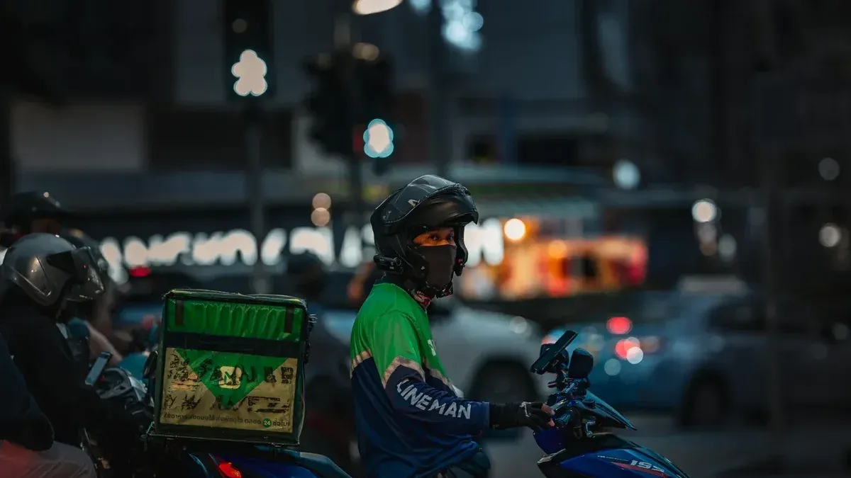 Food delivery rider on motorbike at night in Bangkok, Thailand.