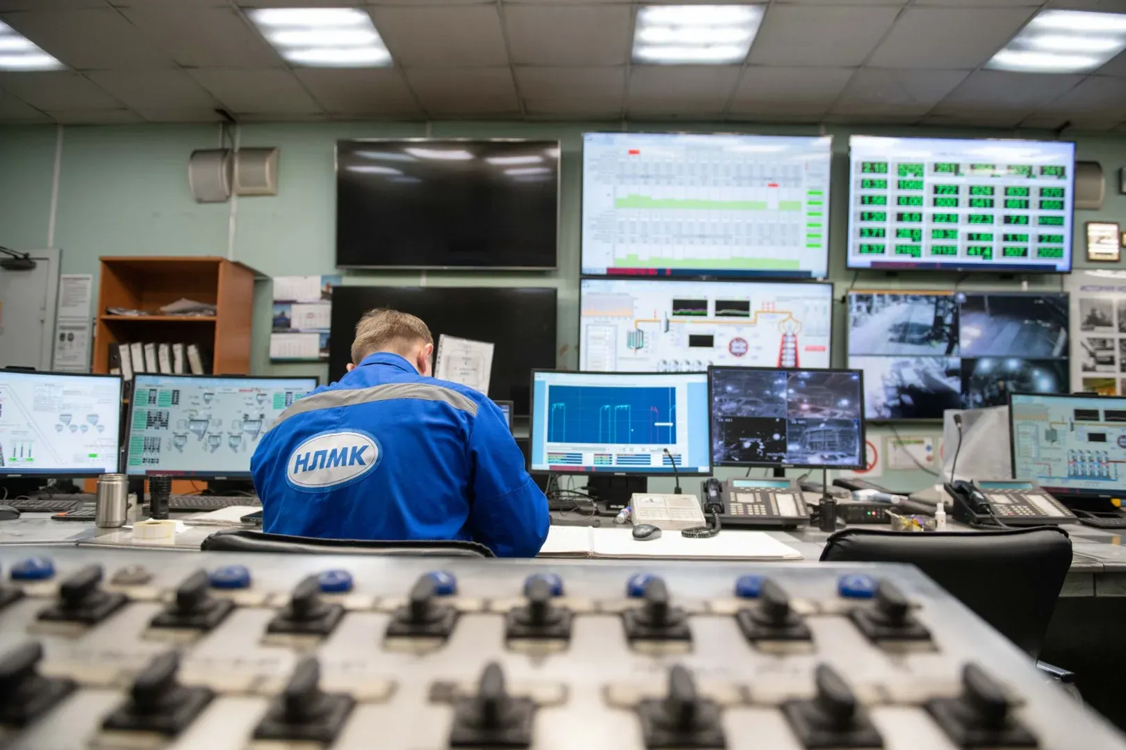 An engineer monitors multiple screens in an industrial control room, ensuring smooth operations.