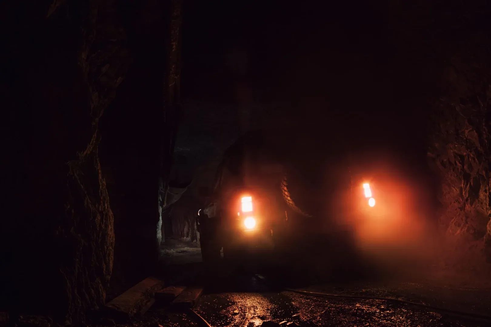 An off-road vehicle with headlights on in a dark underground tunnel in BC, Canada.