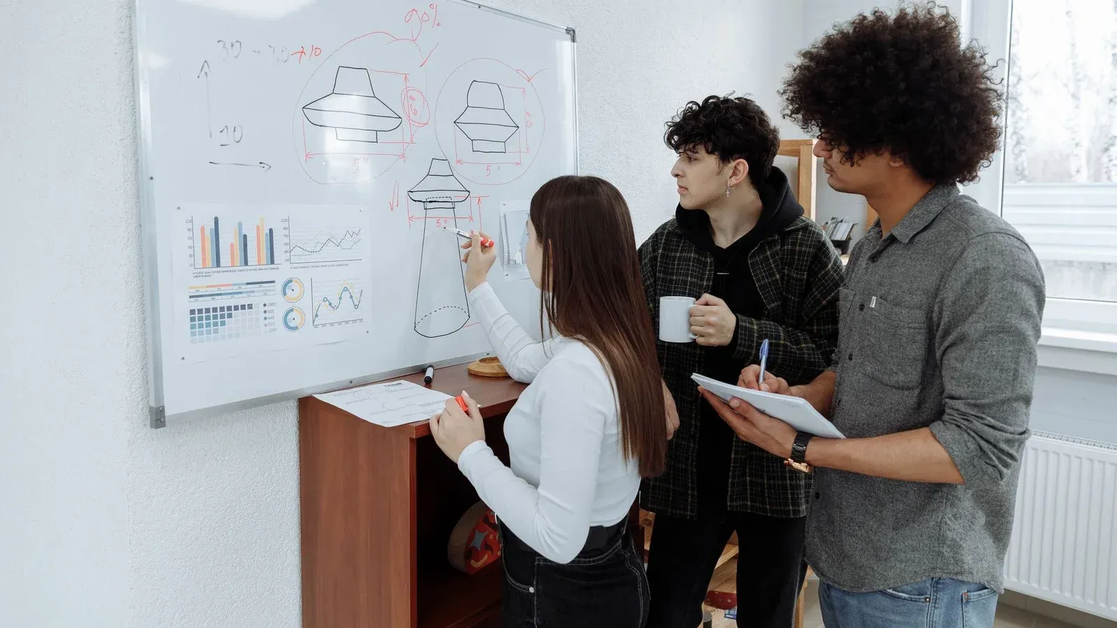 Young professionals brainstorming and designing a product prototype on a whiteboard.