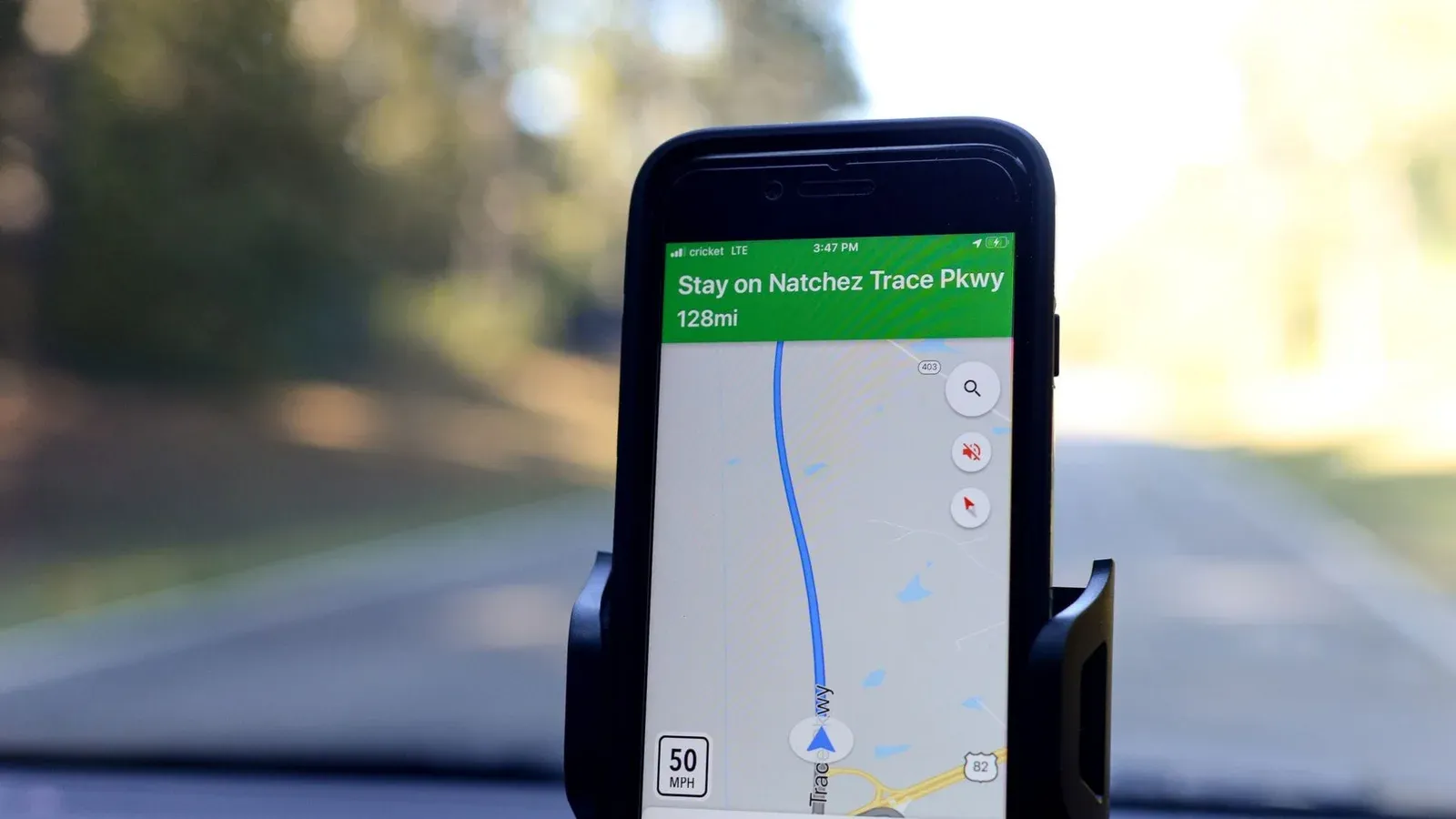Smartphone displaying GPS navigation route on Natchez Trace Parkway inside a car.