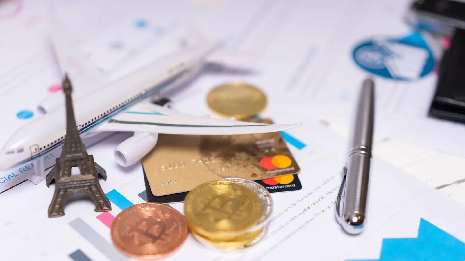 A travel finance concept featuring cryptocurrency, credit card, airplane model, and Eiffel Tower on financial documents.