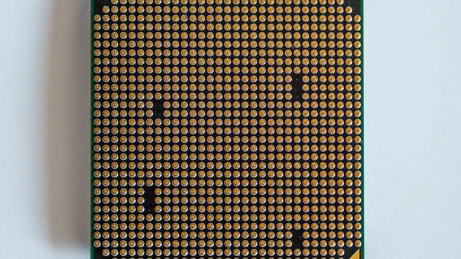 Detailed view of a computer processor, showcasing its pins, against a clean white backdrop.