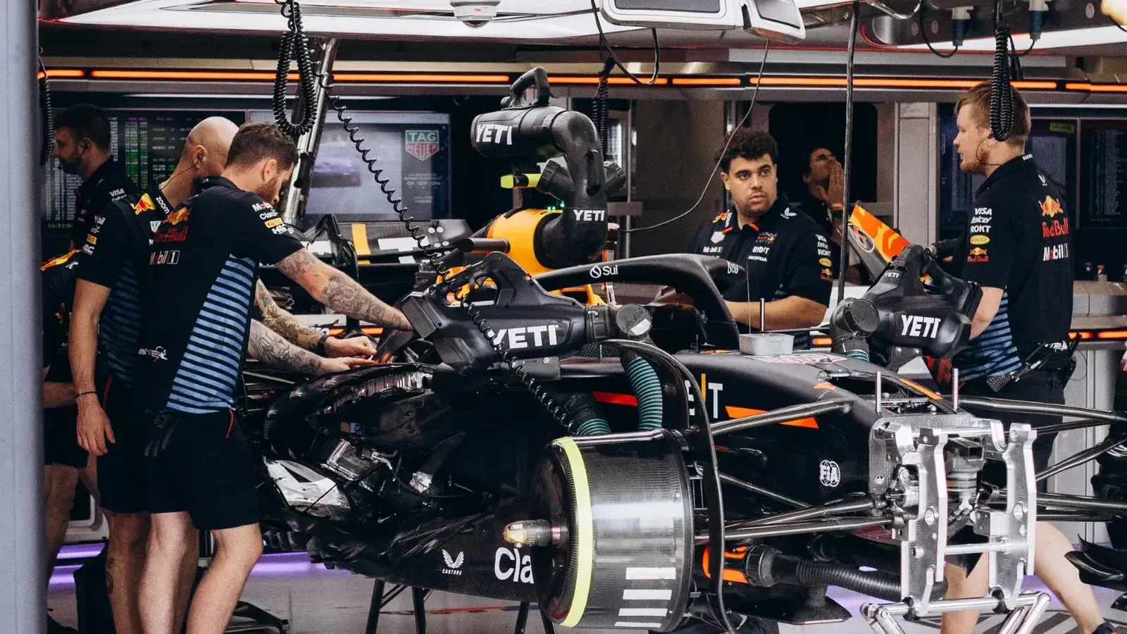 Formula 1 team mechanics work on a race car in the garage, preparing for the competition.