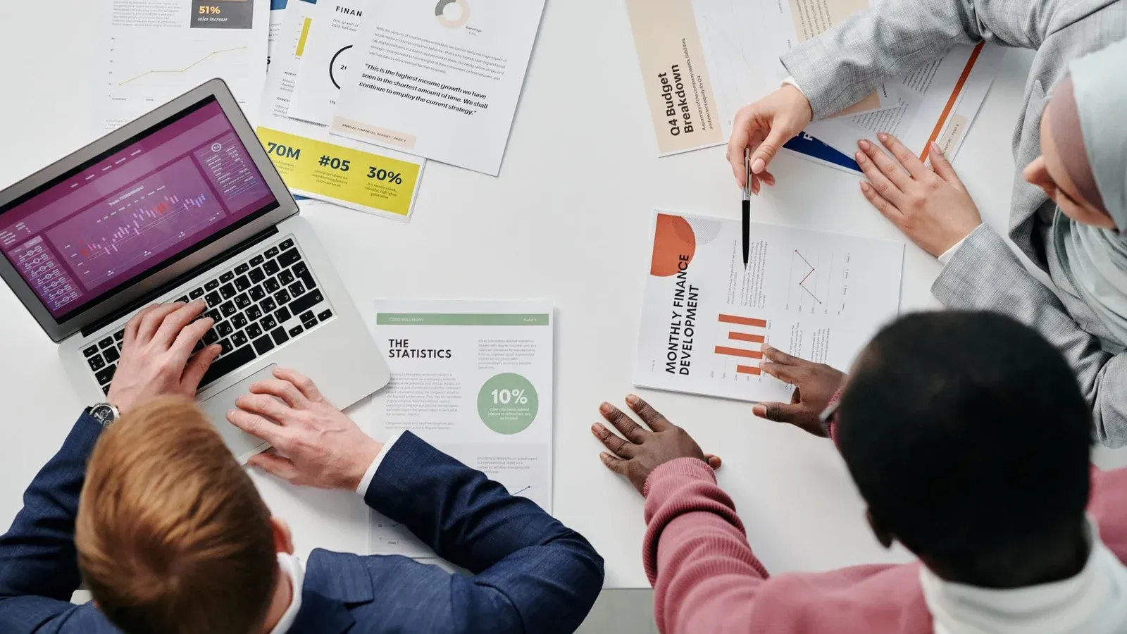 Business meeting with professionals discussing financial reports and graphs at a work desk.