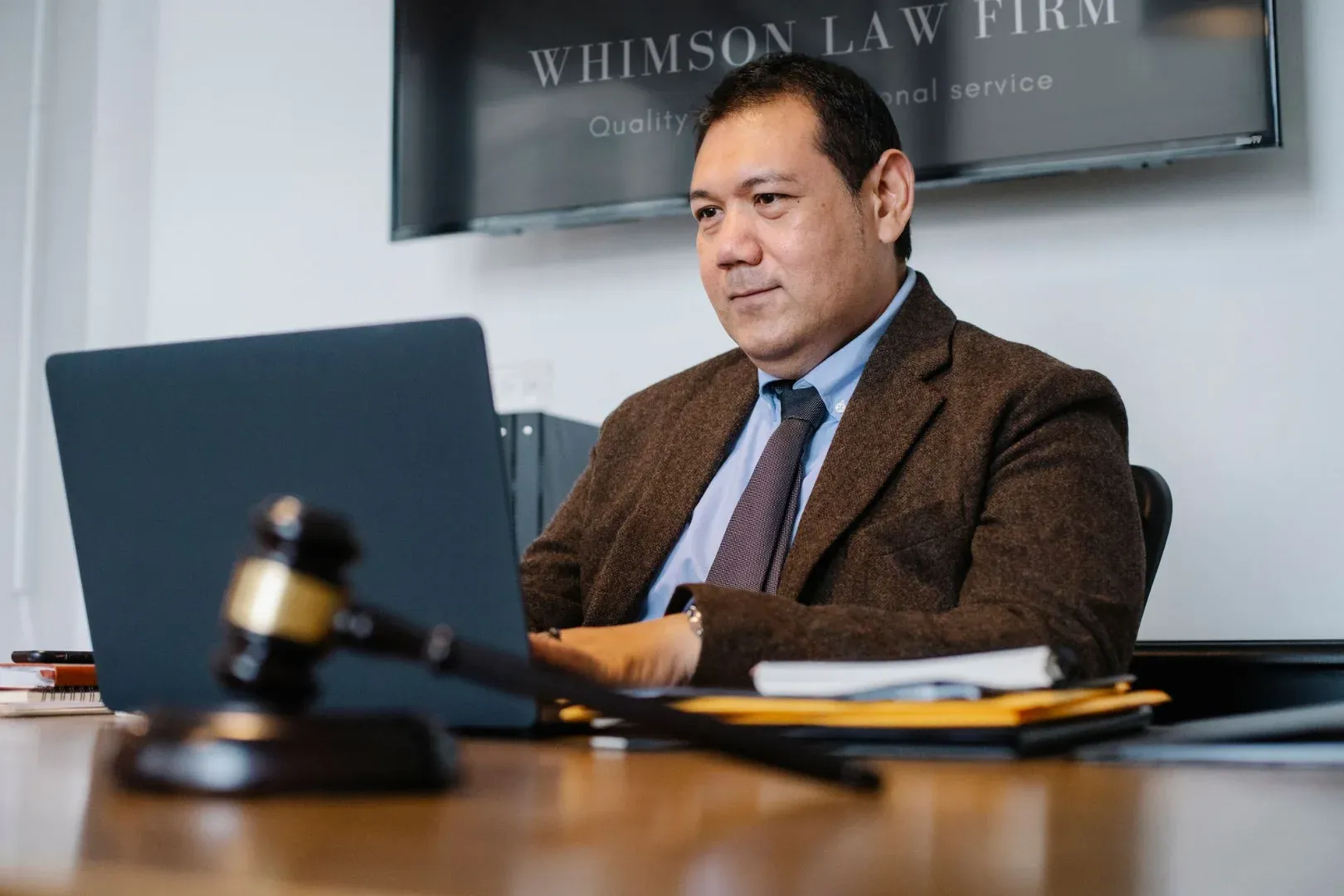 Content adult Asian male lawyer in elegant formal suit surfing contemporary netbook while working in respectable law firm