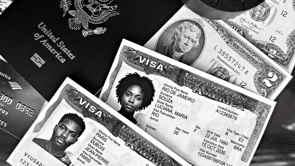 A black and white composition of a US passport, visas, and currency, showcasing travel essentials.