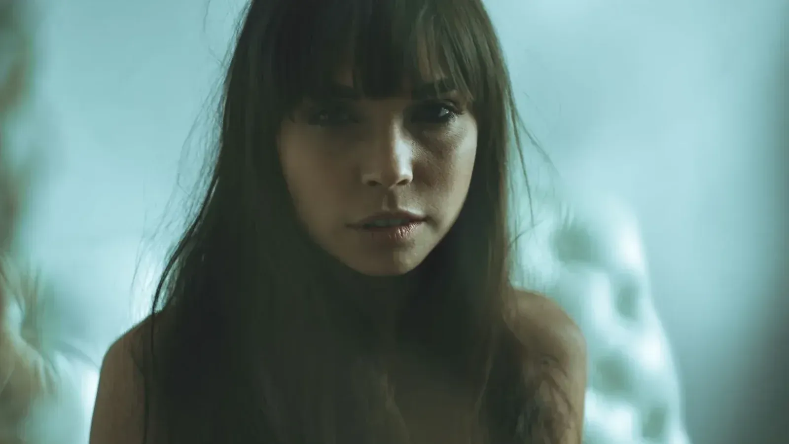 Artistic portrait of a woman with long hair and bangs in a soft, moody setting.