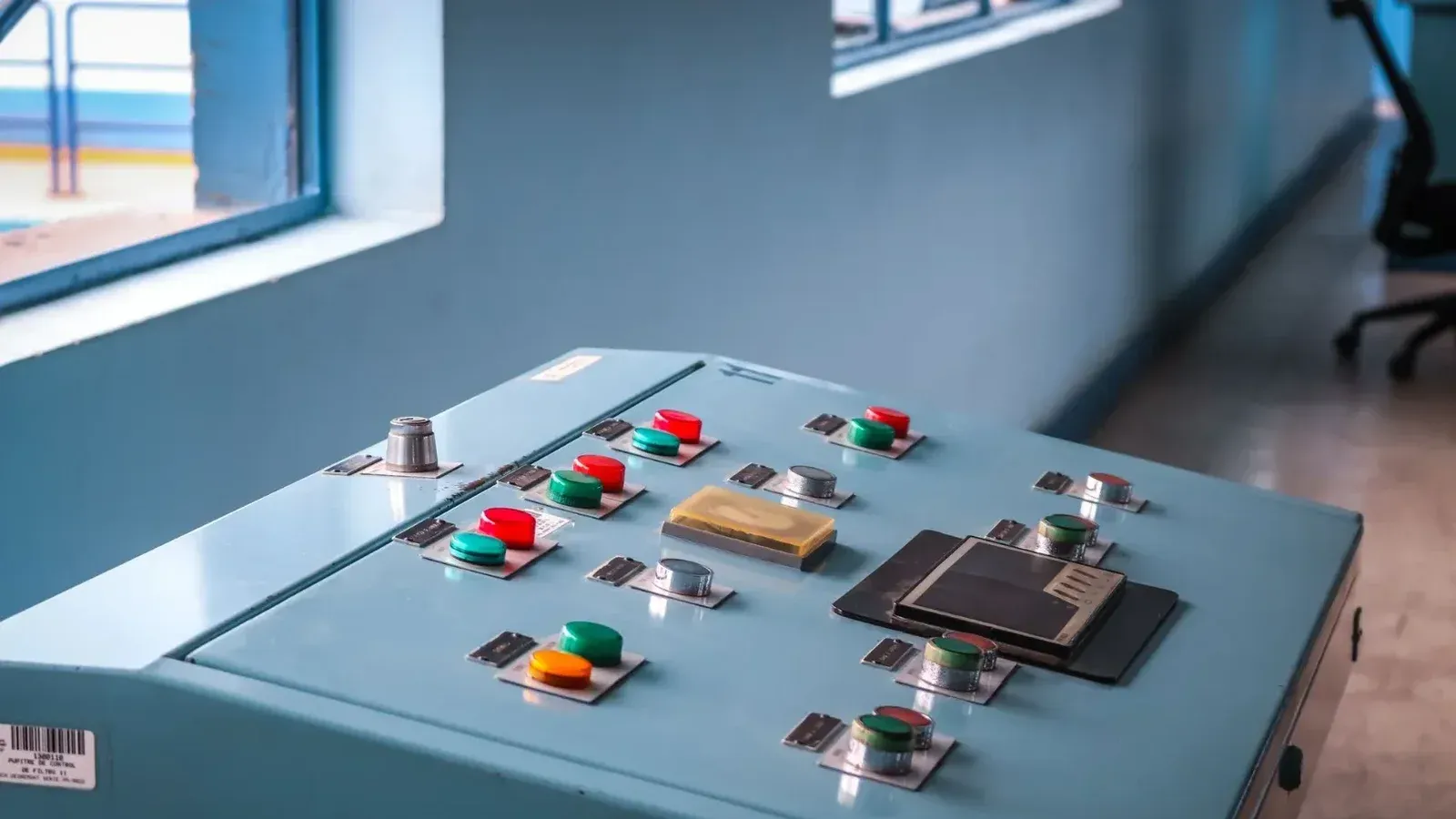 Close-up of an industrial control panel with colorful buttons in a factory setting.